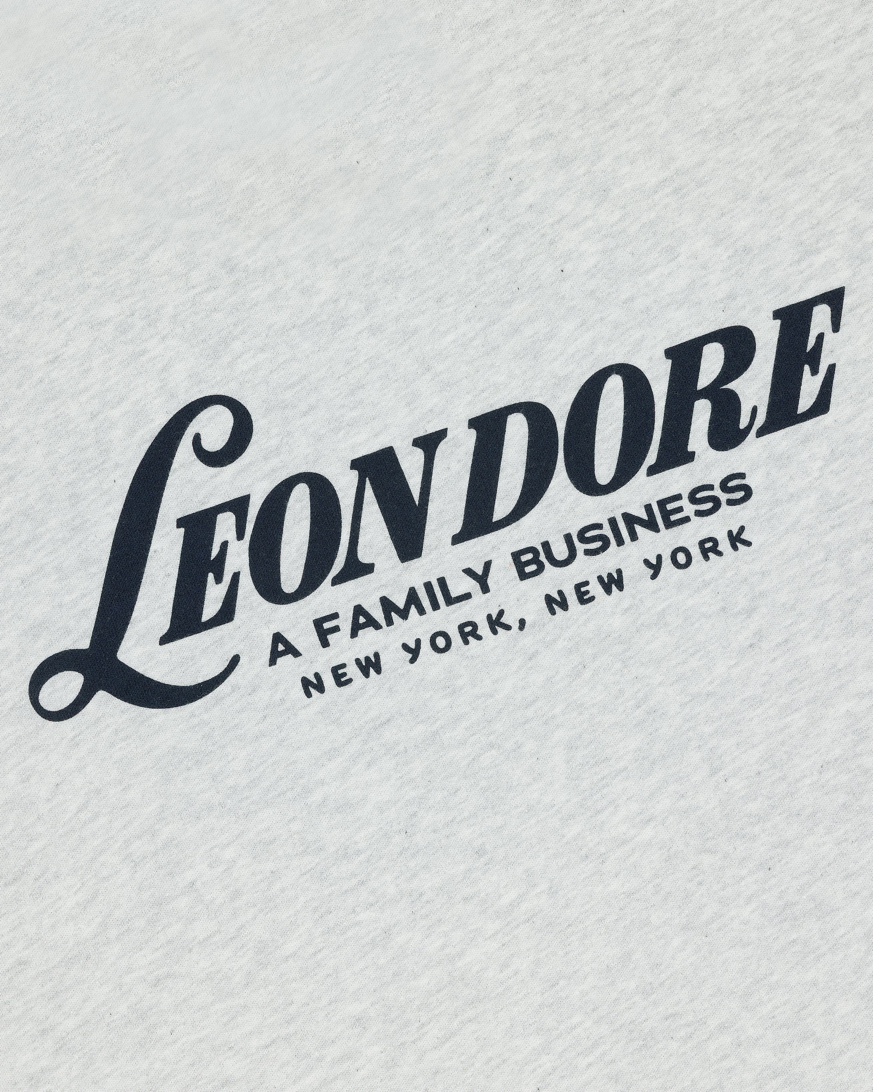White Leon Dore Tee featuring bold black "A FAMILY BUSINESS NEW YORK, NEW YORK" text on white fabric.