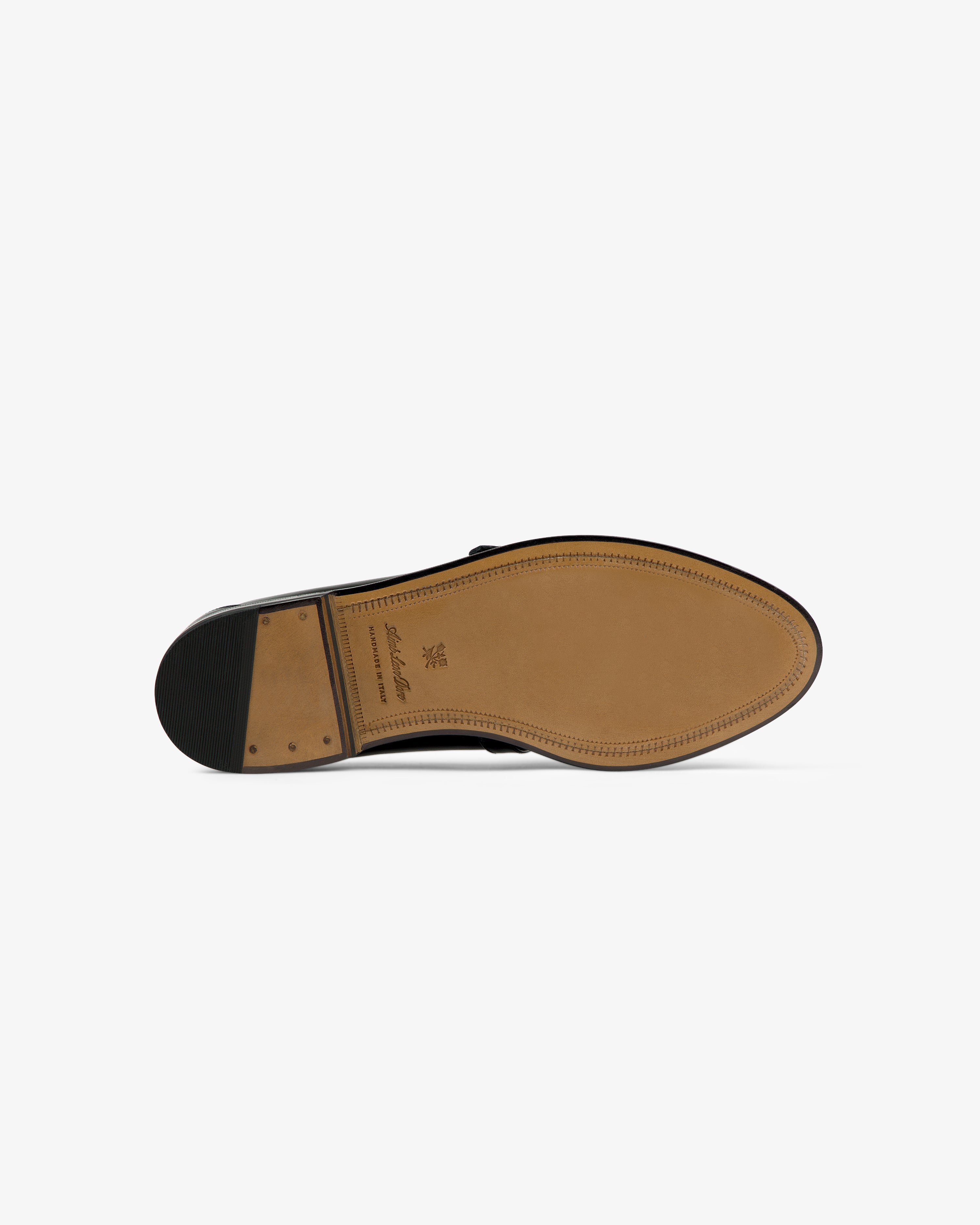 Bottom view of the Venetian Buckle Loafer with a tan leather sole and black rubber heel on white background.