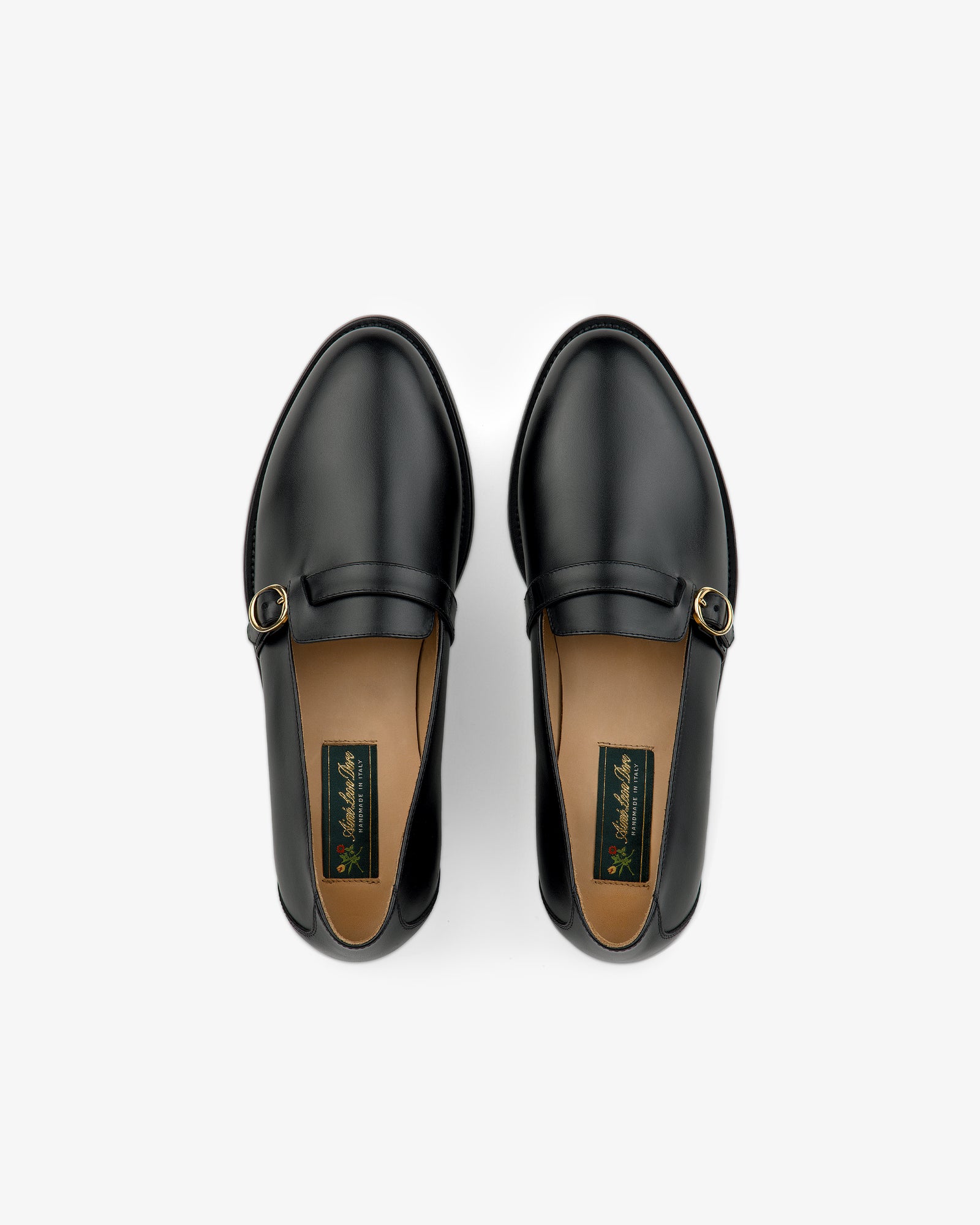 Venetian Buckle Loafers in black leather with gold buckles, top view on a white background.
