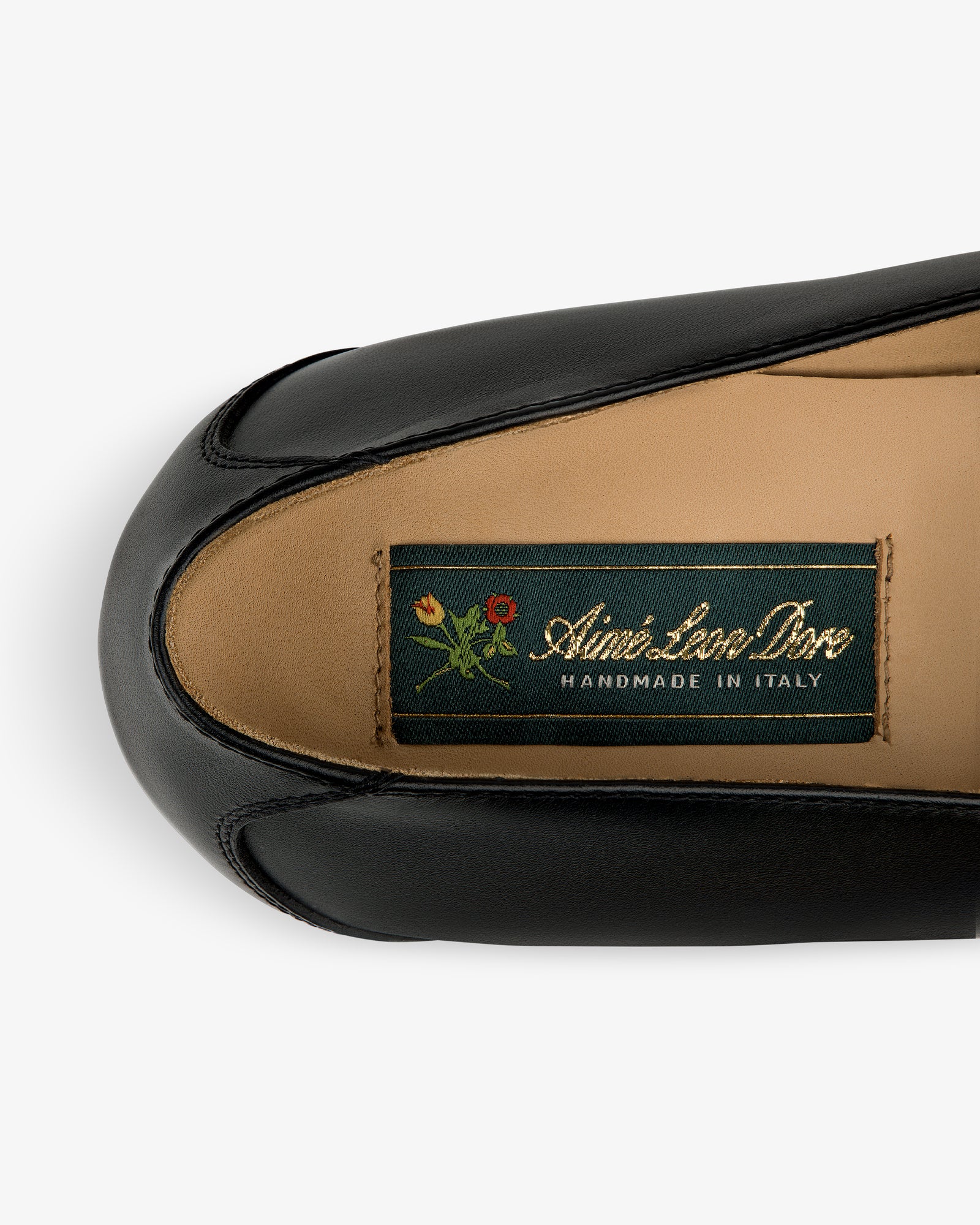 Venetian Buckle Loafer in black leather with “Aimé Leon Dore Handmade in Italy” tag and small flower graphic.