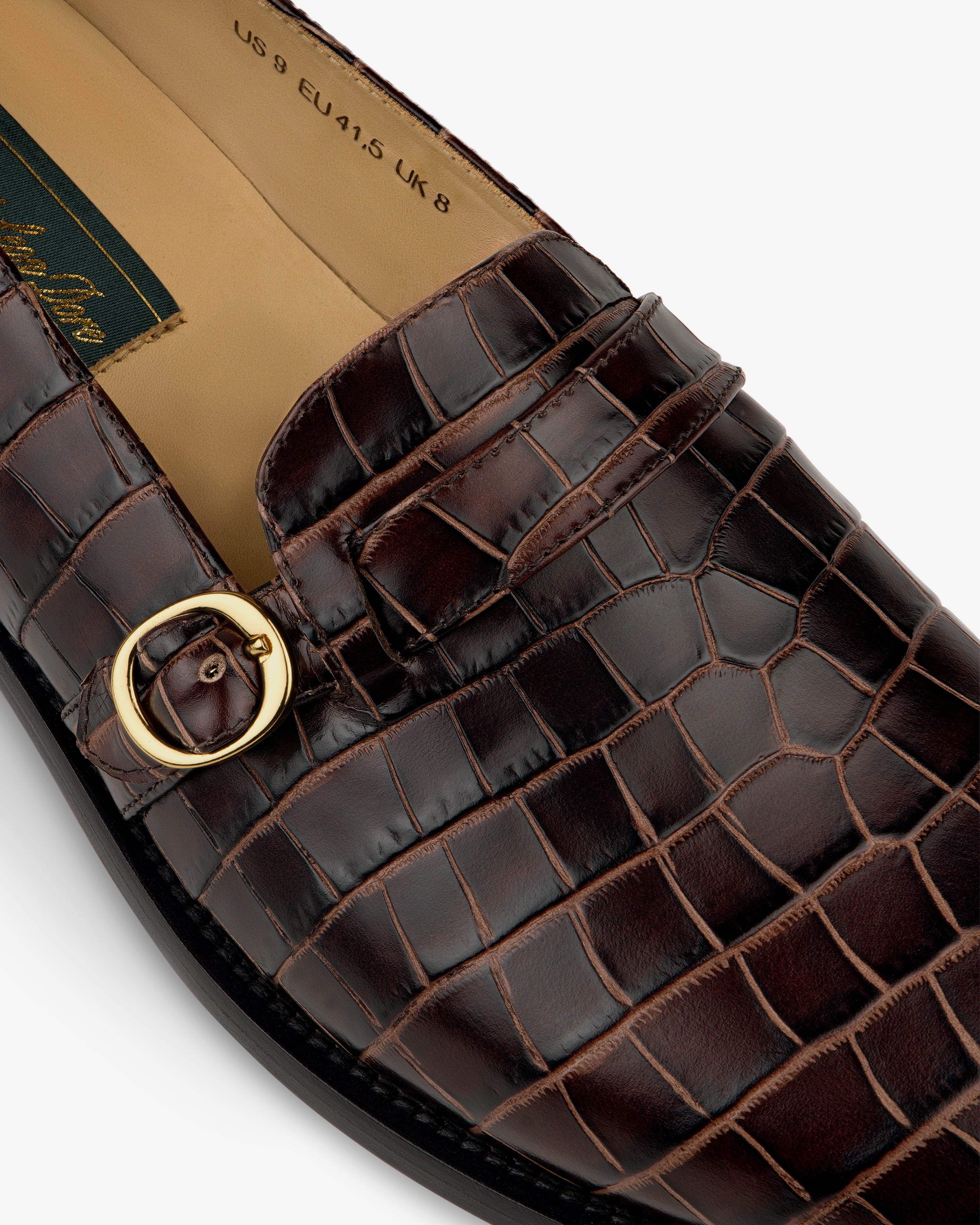 Close-up of the Venetian Croc Buckle Loafer in brown, featuring a gold buckle and visible interior size label.