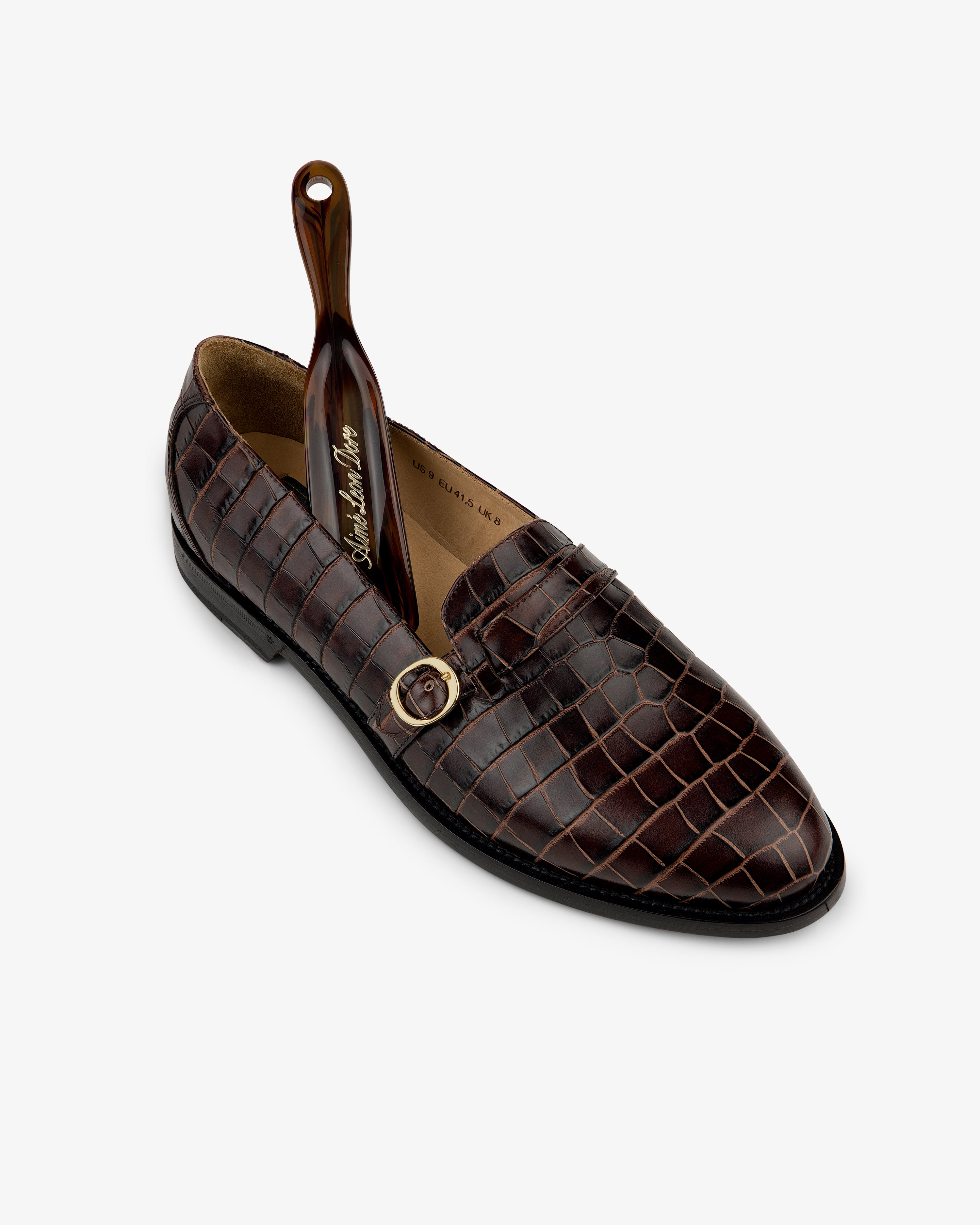 Venetian Croc Buckle Loafer in brown with crocodile pattern, shown with a small dark brown shoehorn inside.