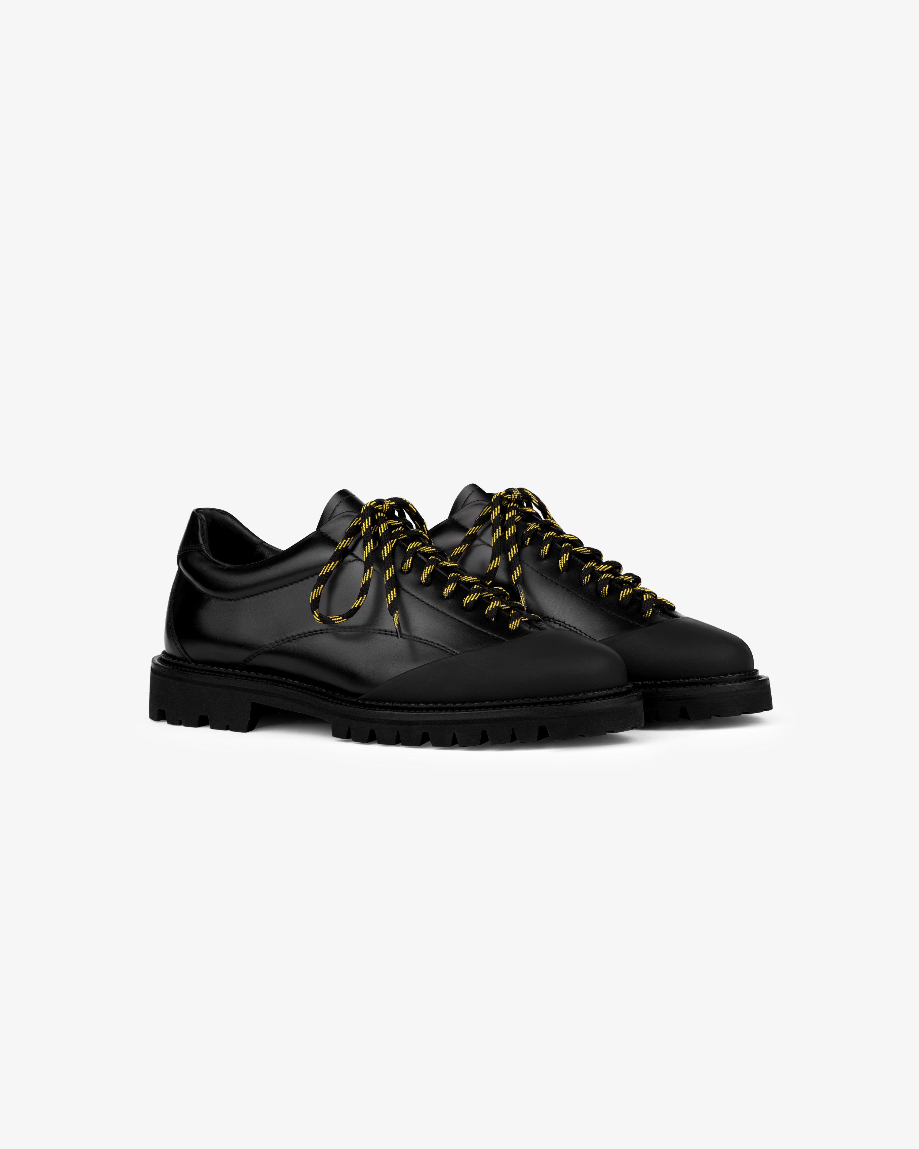 Leather Derby Hiker: black leather lace-up shoes with chunky soles, yellow-black striped laces, on white background.