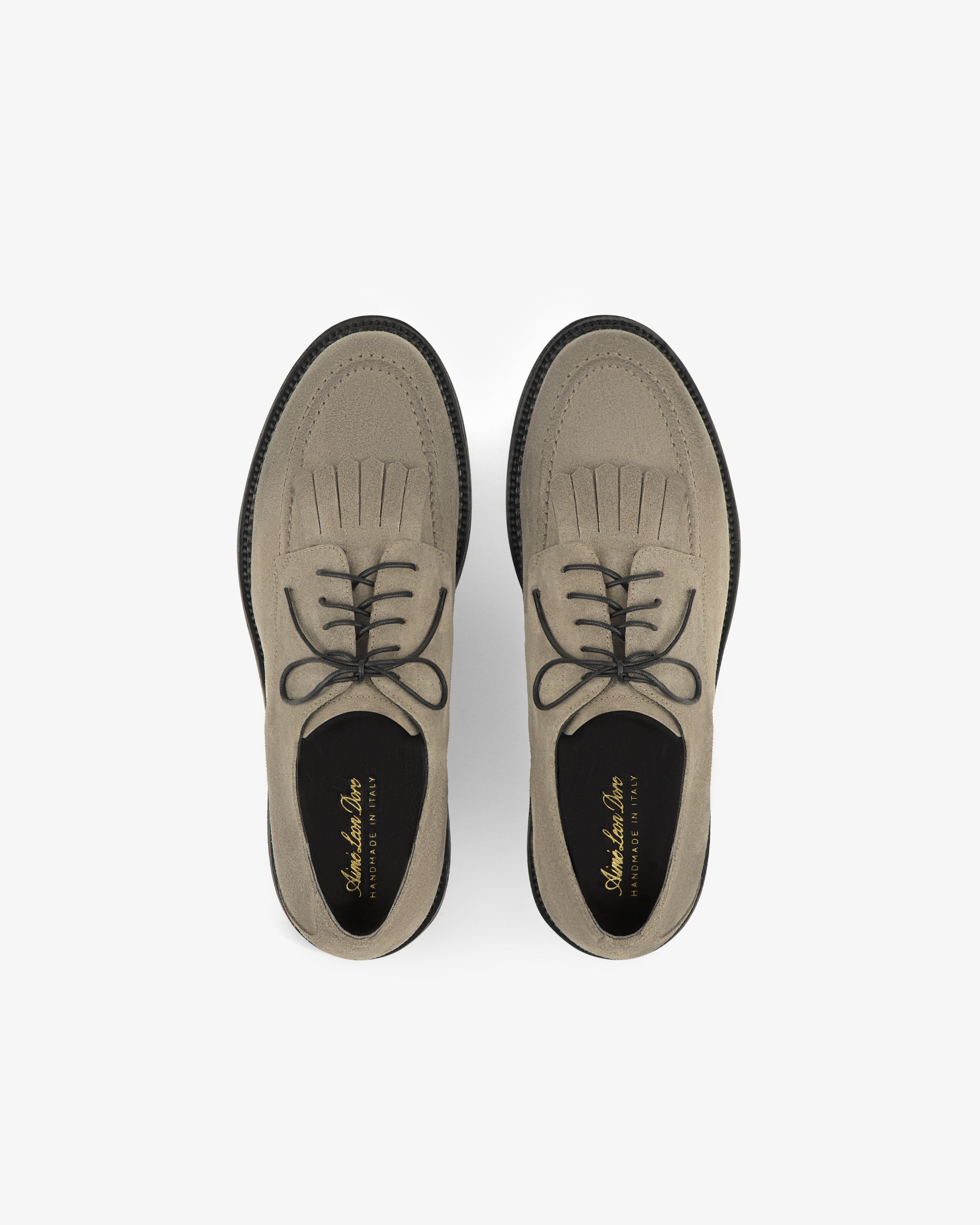 Top view of Suede Lug Sole Derby shoes in light brown, with black laces and soles, on a white background.