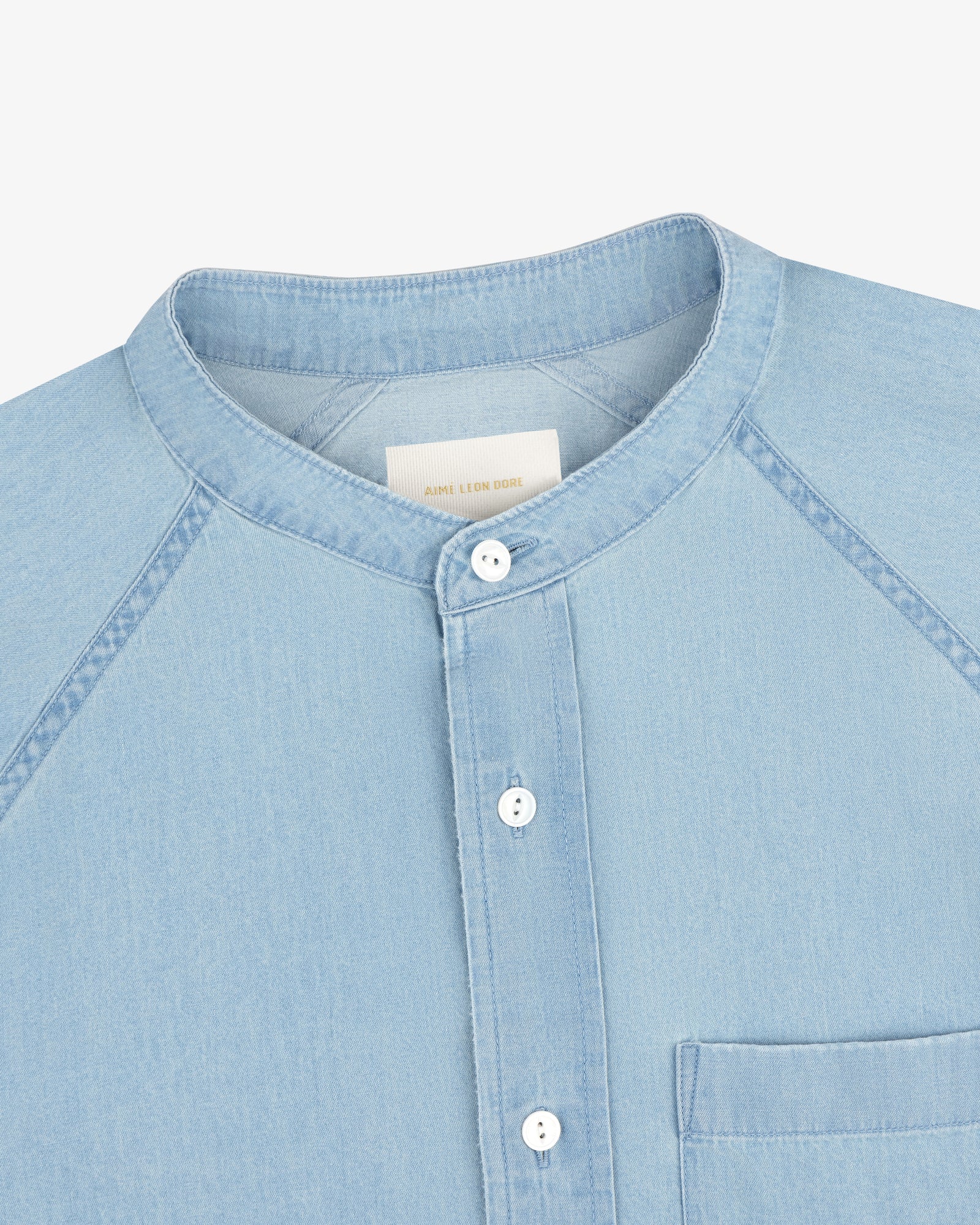 Denim Collarband Shirt in light blue with a band collar, white buttons, and front chest pocket, shown from the front.