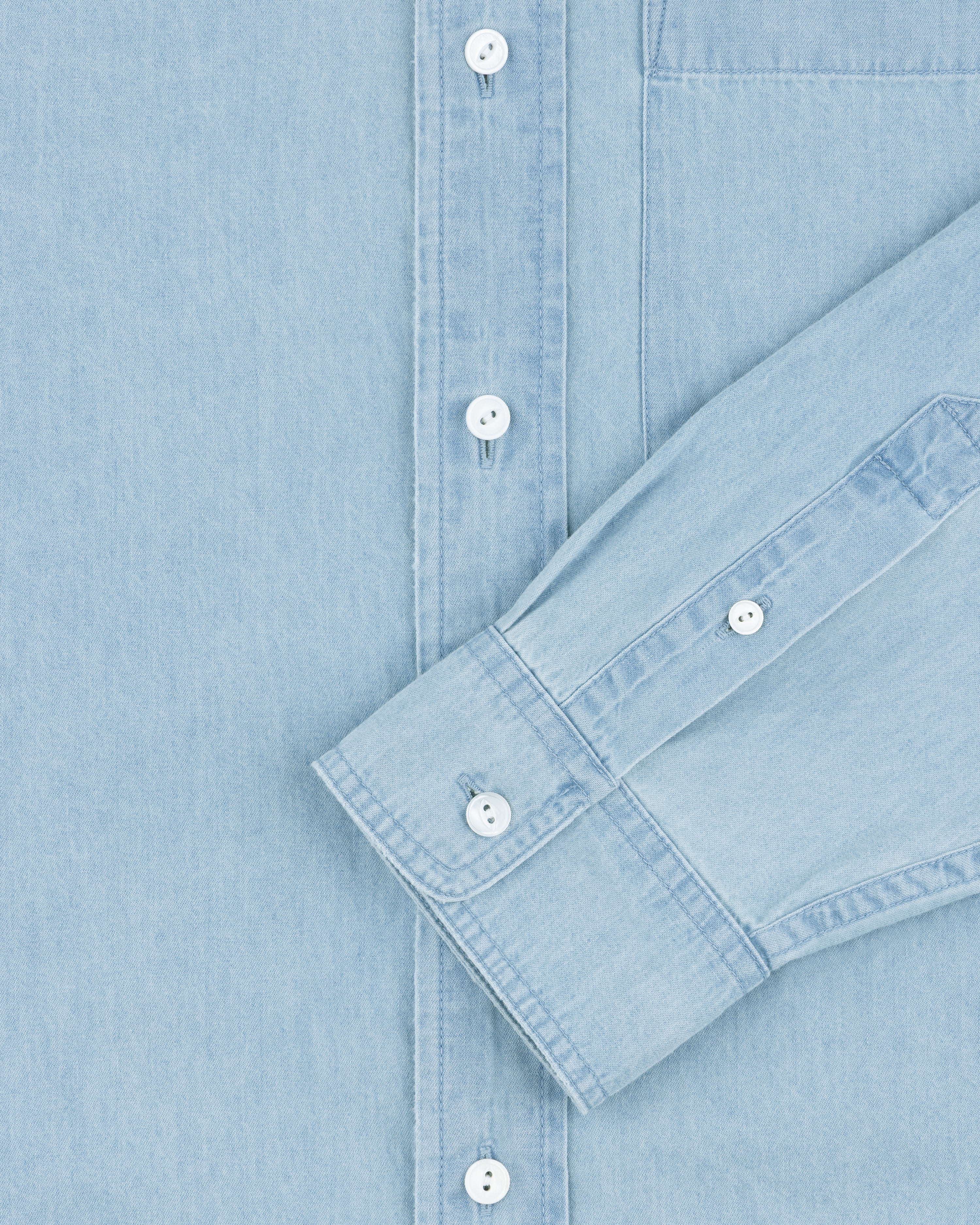 Denim Collarband Shirt in light blue with white buttons, front view, one sleeve folded across the chest.