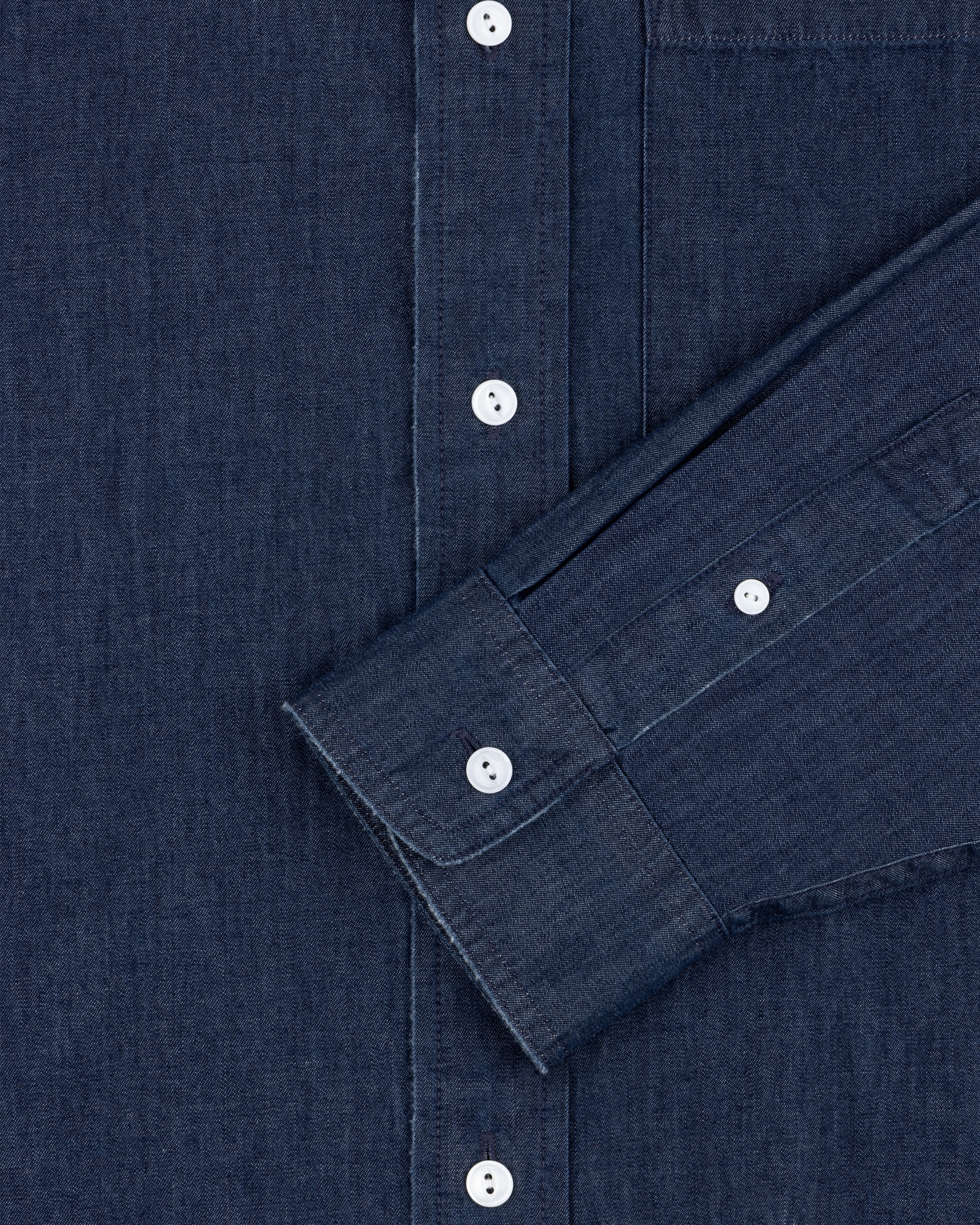 Close-up of the Denim Collarband Shirt in dark blue with white buttons, chest pocket, and sleeve visible.
