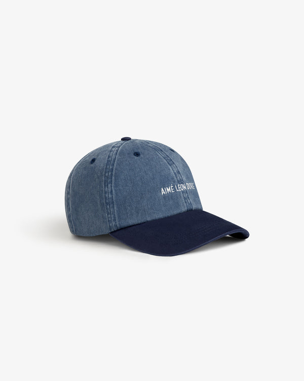 Pigment Dyed Logo Hat in blue denim with navy brim and white embroidery, shown on a white background.