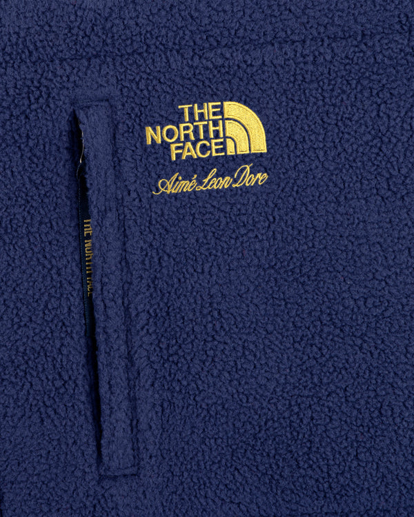 Close-up of a blue ALD / The North Face Denali Fleece Scarf with yellow embroidered logo and zippered pocket.