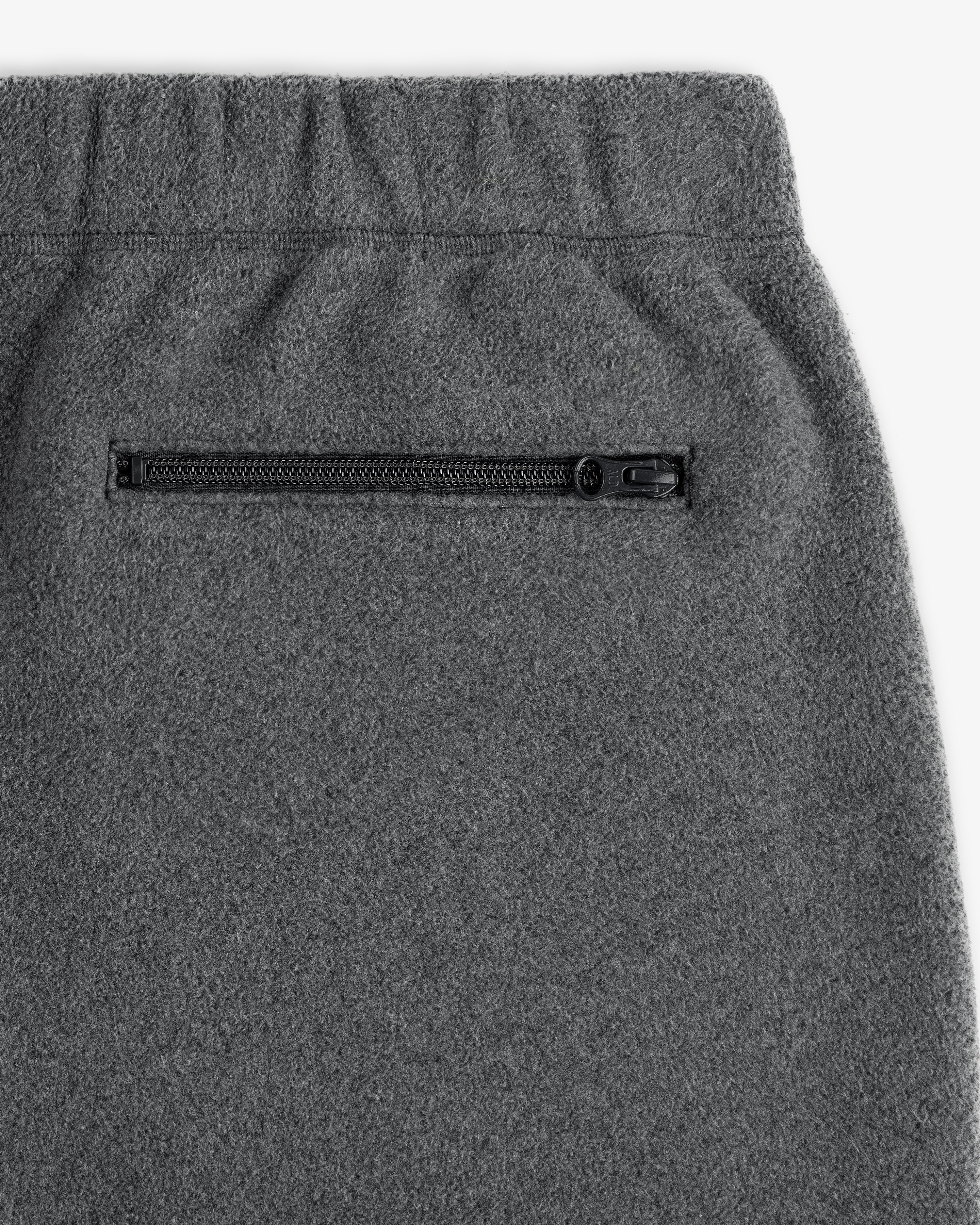 Close-up of Crest Fleece Sweatpant in gray with an elastic waistband and black zippered side pocket.