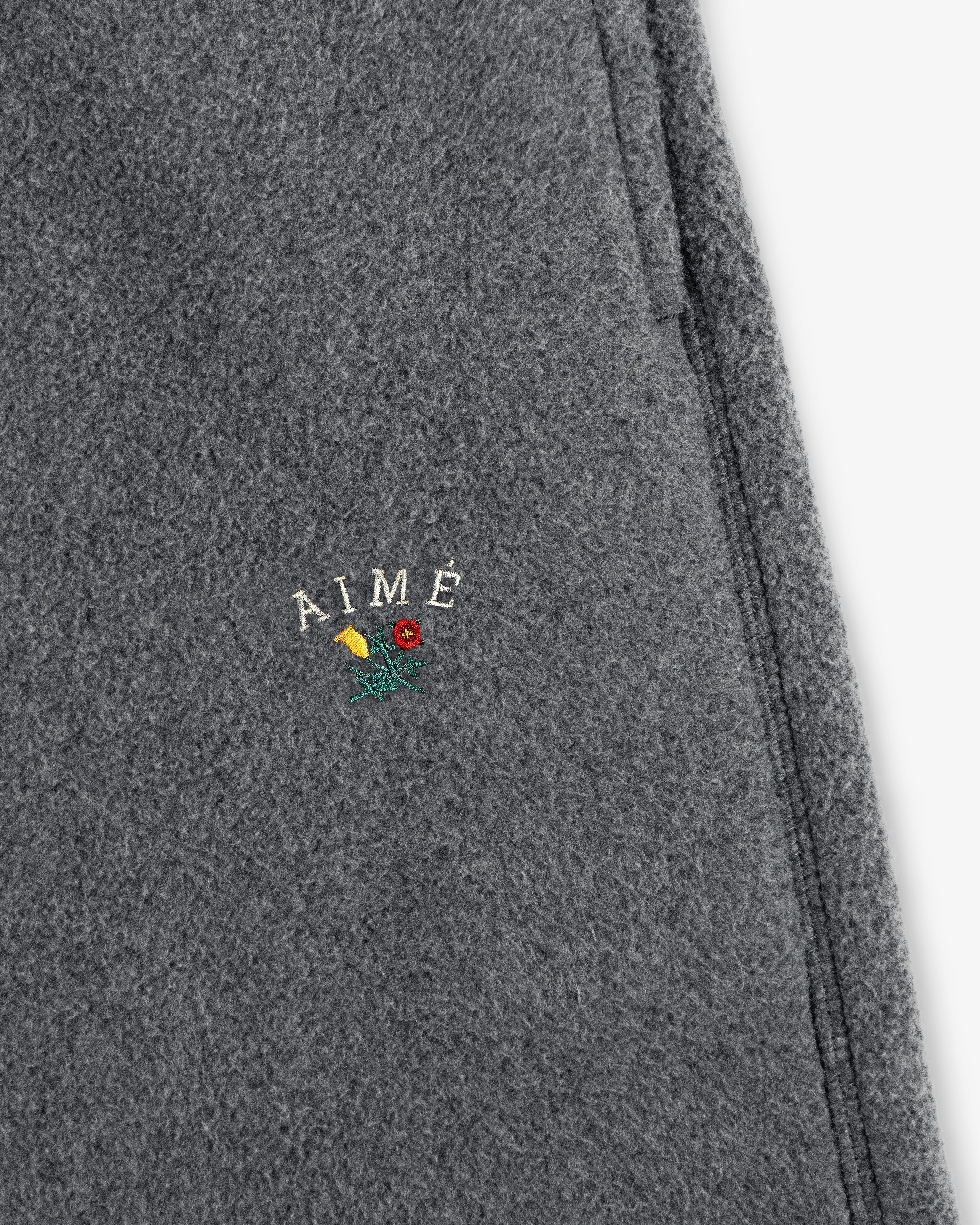 Gray wool Crest Fleece Sweatpant with AIMÉ embroidered above a small yellow and red flower with green stem.