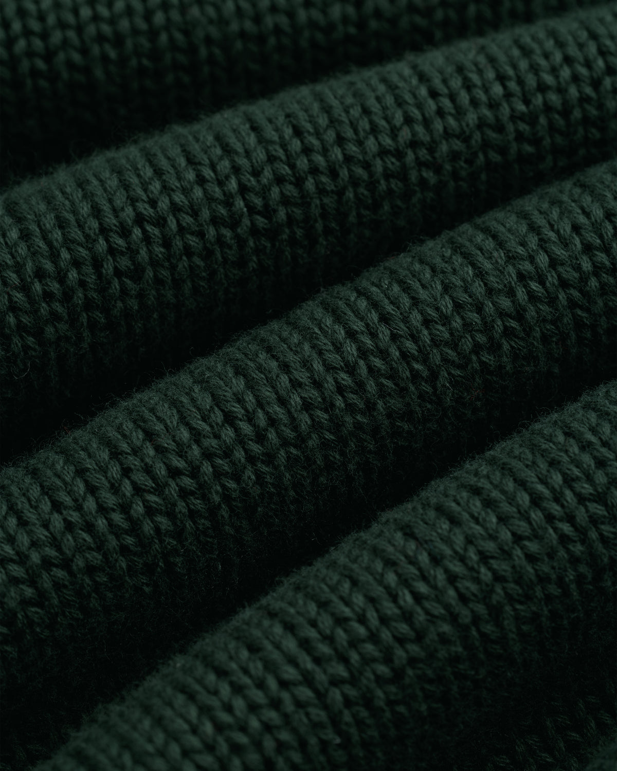 Close-up of Crest Raglan Sweater: dark green ribbed knit with textured horizontal rows and soft fibers.
