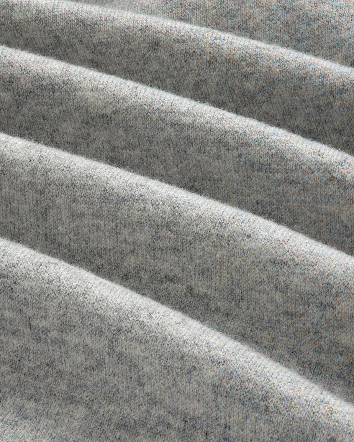 Close-up of folded, soft Pavilion Cashmere Hoodie in heather gray, showing texture and diagonal, parallel folds.