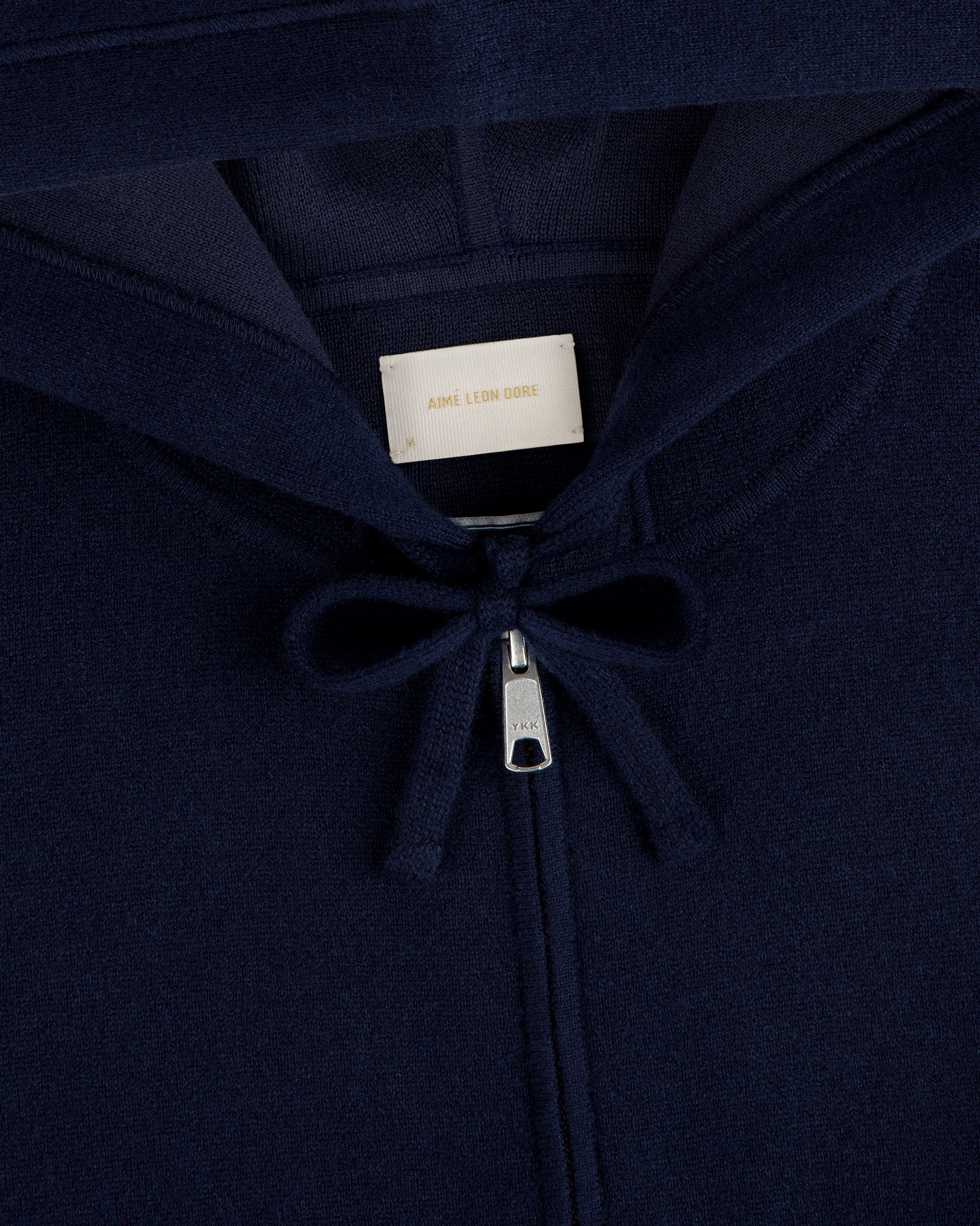 Close-up of the Full-Zip Pavilion Cashmere Hoodie in navy blue, featuring a zipper, drawstring, and beige collar label.