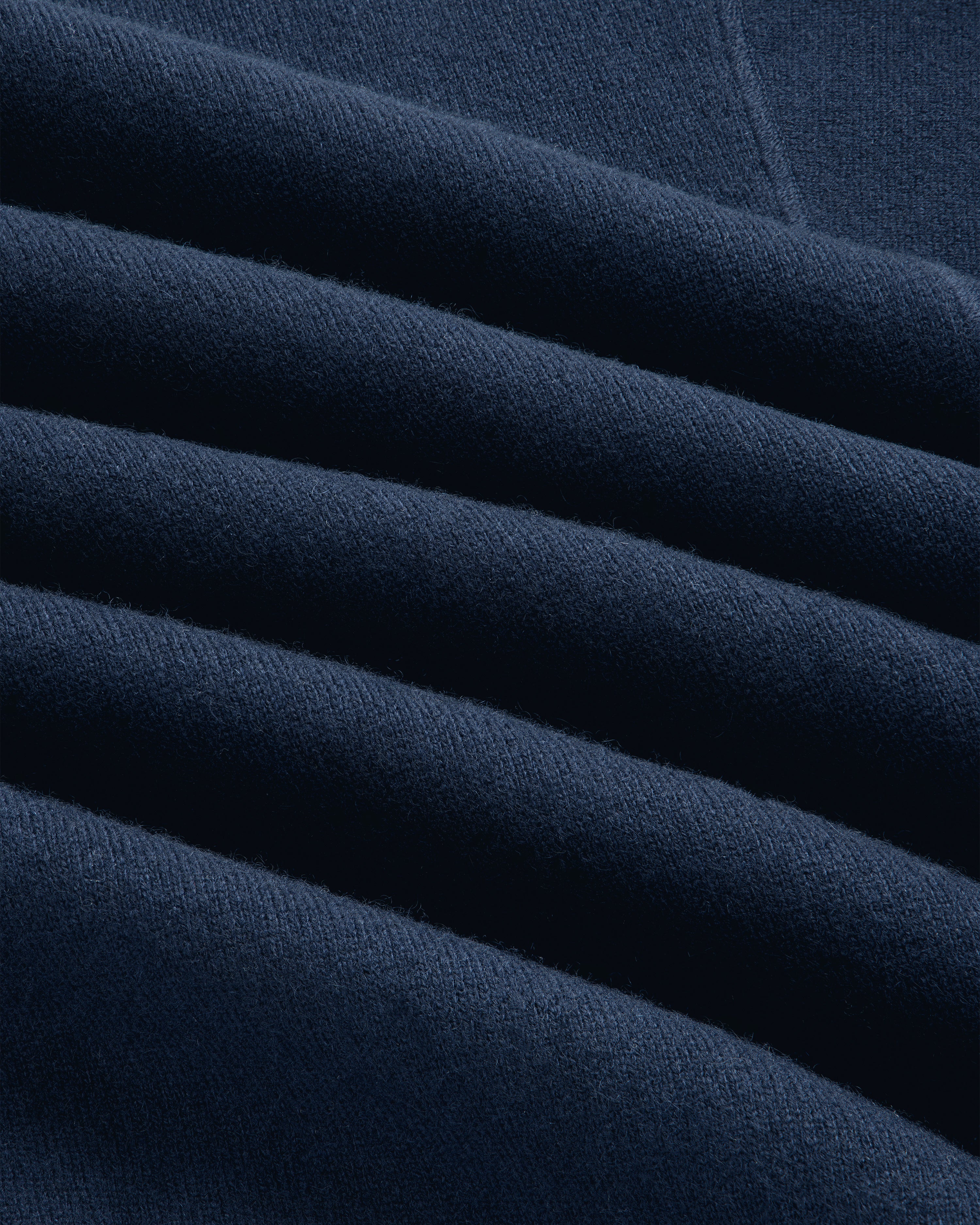 Close-up of folded navy Pavilion Cashmere Pullover with textured fabric and soft, even lighting.