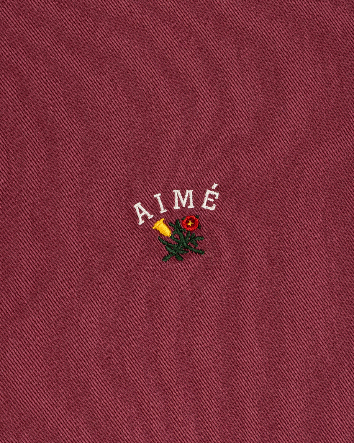 Garment Dyed Leon Overshirt: red with white AIMÉ text, yellow rose, and green leaves embroidery.