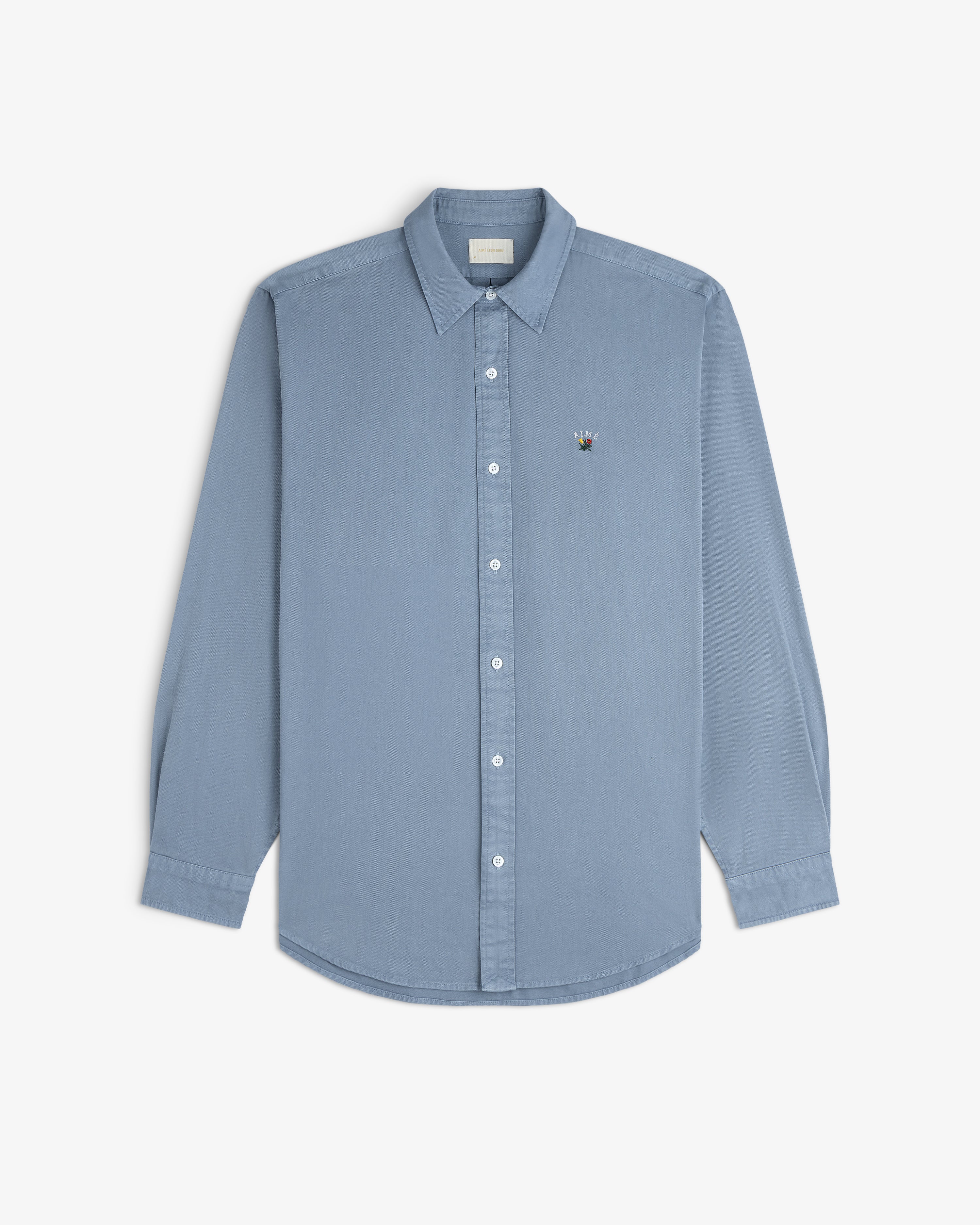 Garment Dyed Leon Overshirt in light blue, long sleeves, button-down, with embroidered crest on left chest.