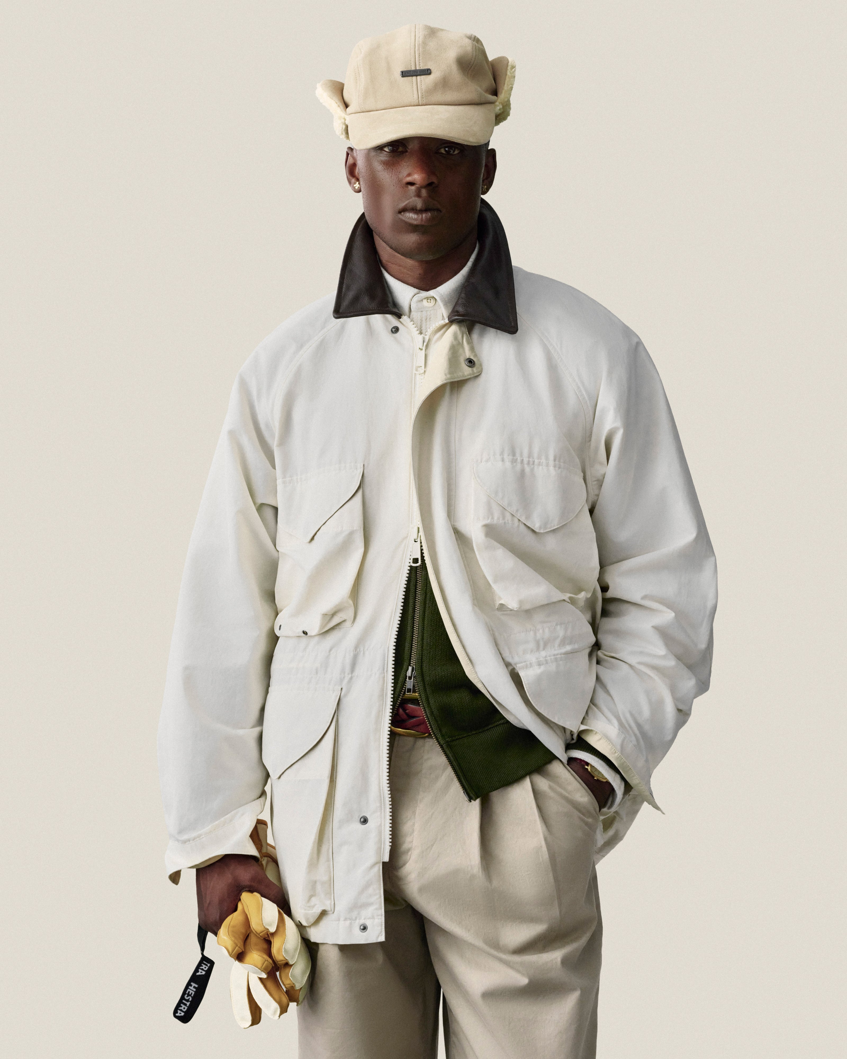Man in Double Pleated Officer Pant and cap, holding yellow gloves, stands against a plain light background.