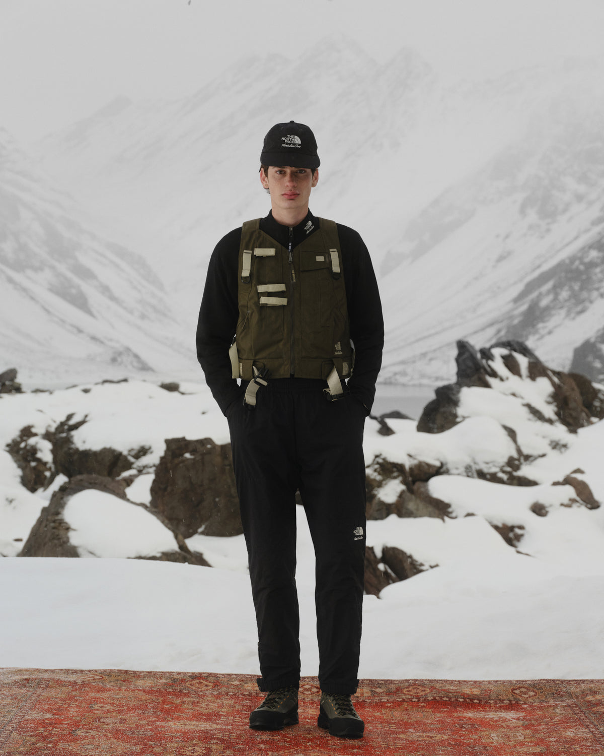 Wearing the ALD / The North Face DOTKNIT™ Wool Quarter Zip, a hiker stands on a snowy mountain with foggy peaks behind.