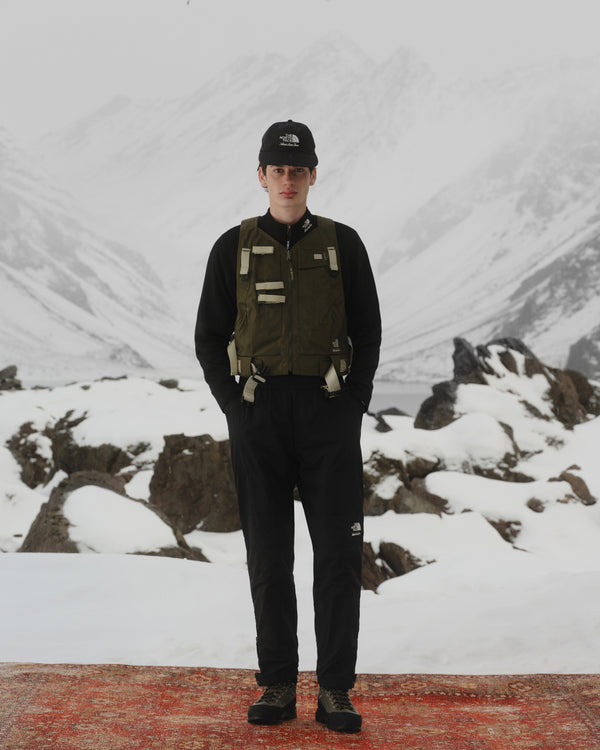 Wearing the ALD / The North Face DOTKNIT™ Wool Quarter Zip, a hiker stands on a snowy mountain with foggy peaks behind.