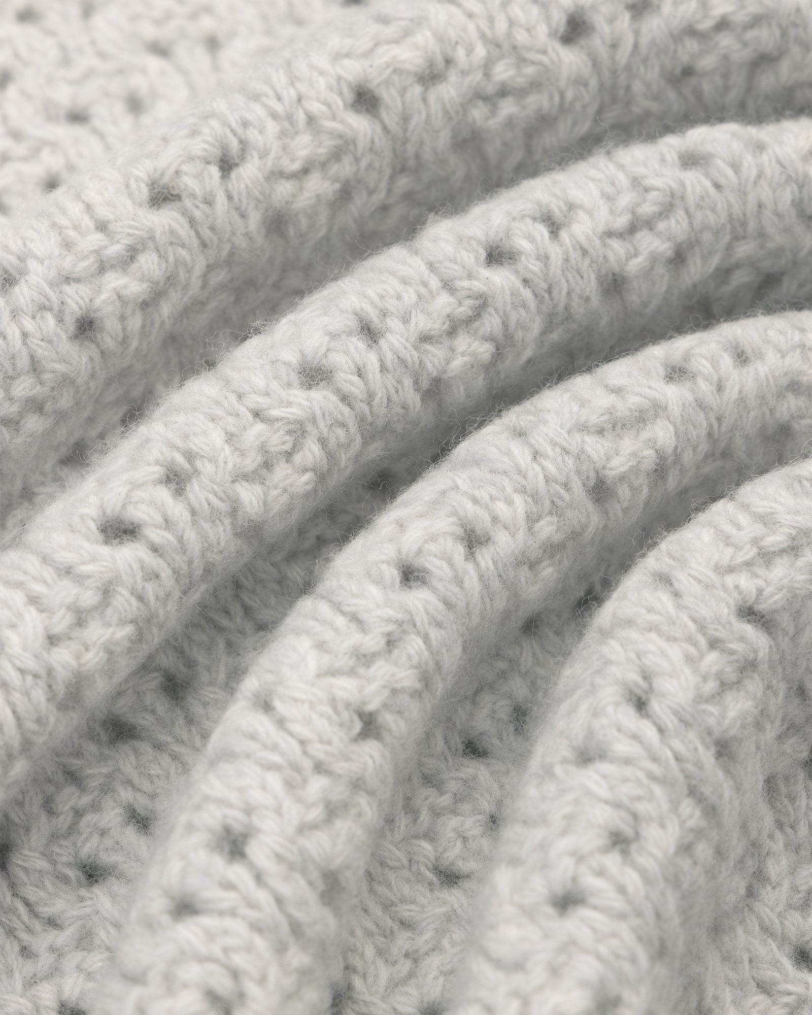 Close-up of soft, textured light gray Knit Polo Cardigan with curved, parallel fabric folds.