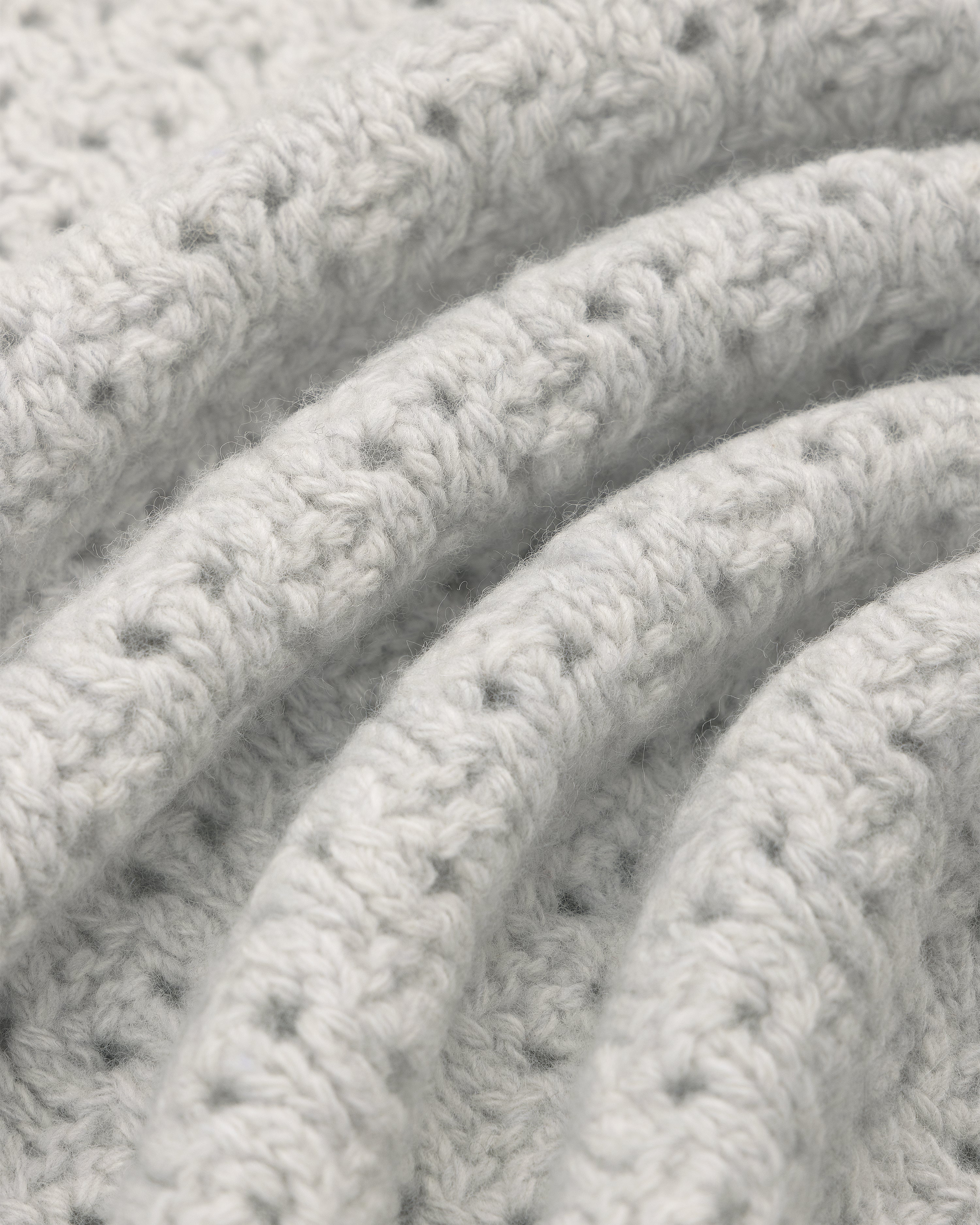 Close-up of soft, textured light gray Knit Polo Cardigan with curved, parallel fabric folds.