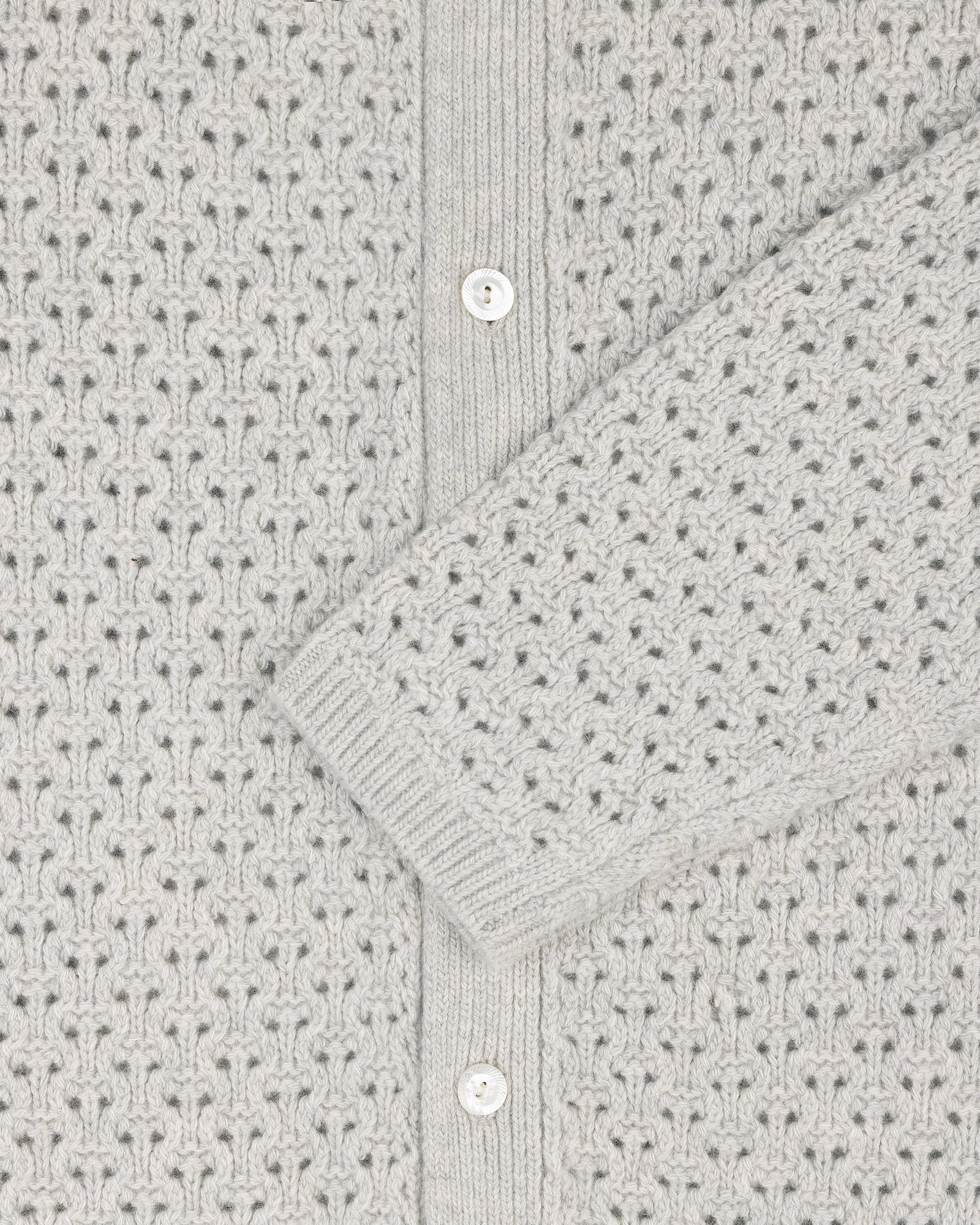 Close-up of a light grey Knit Polo Cardigan with a patterned texture and white buttons.
