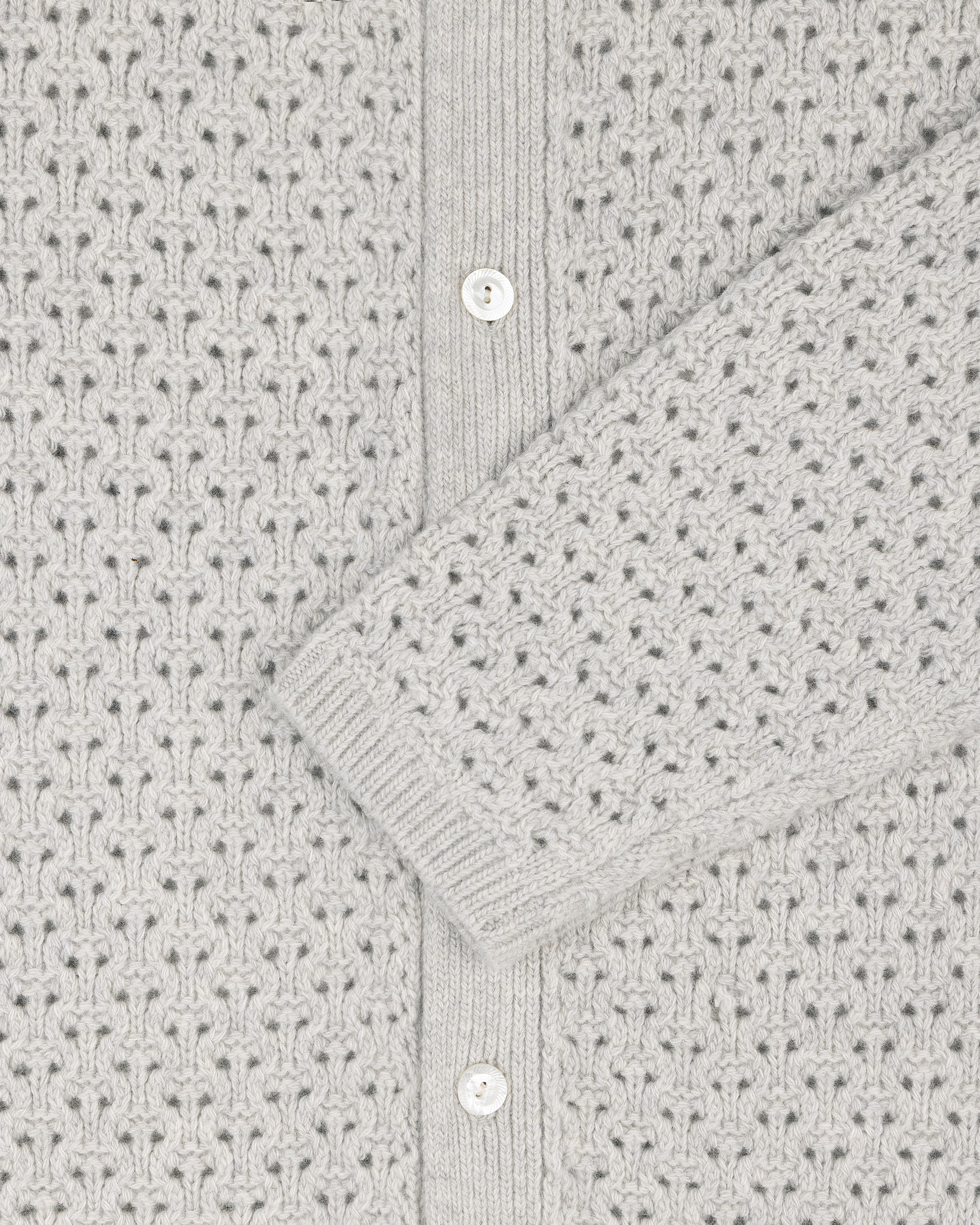 Close-up of a light grey Knit Polo Cardigan with a patterned texture and white buttons.