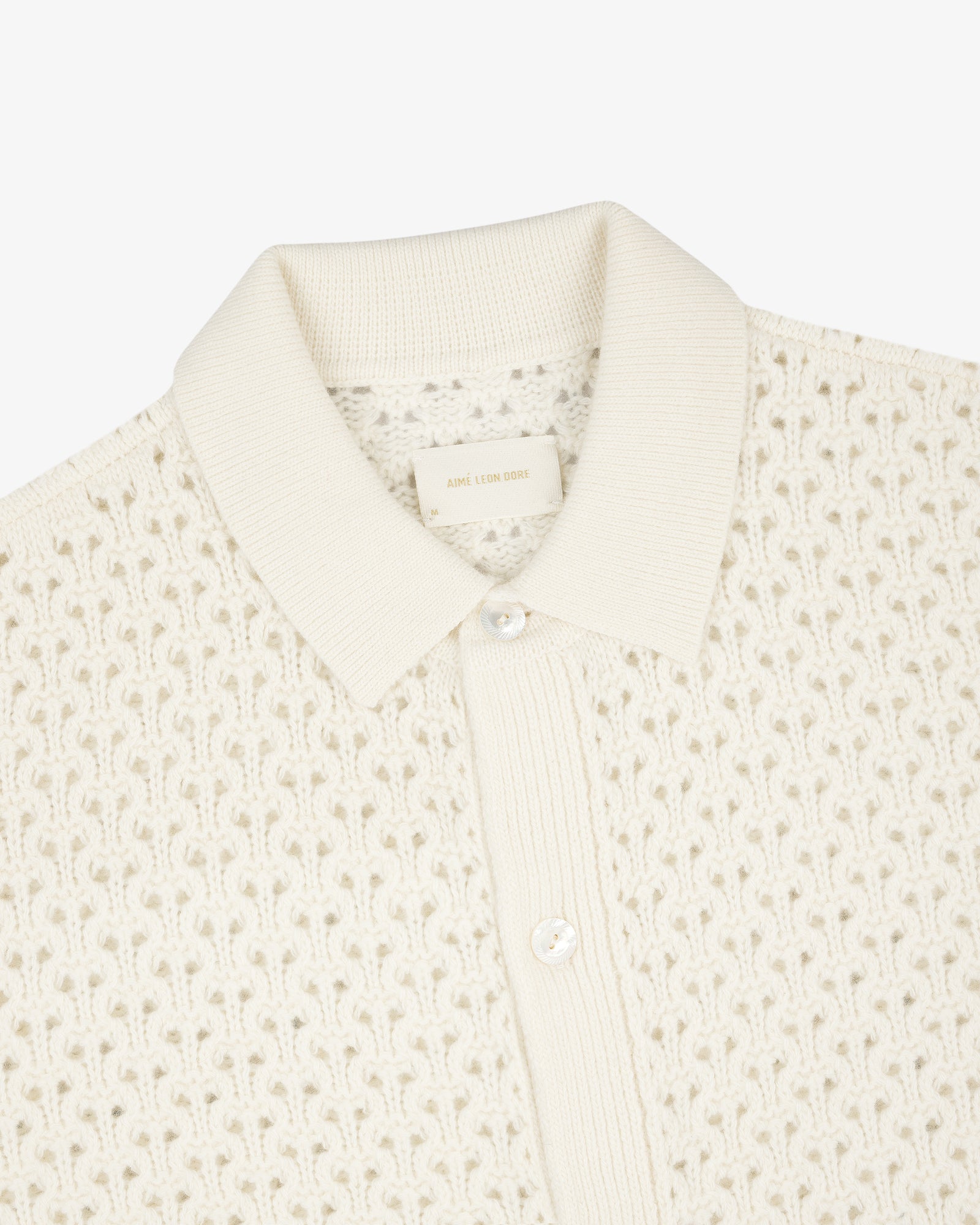 Cream knit polo cardigan with textured pattern, ribbed collar, and two-button placket.