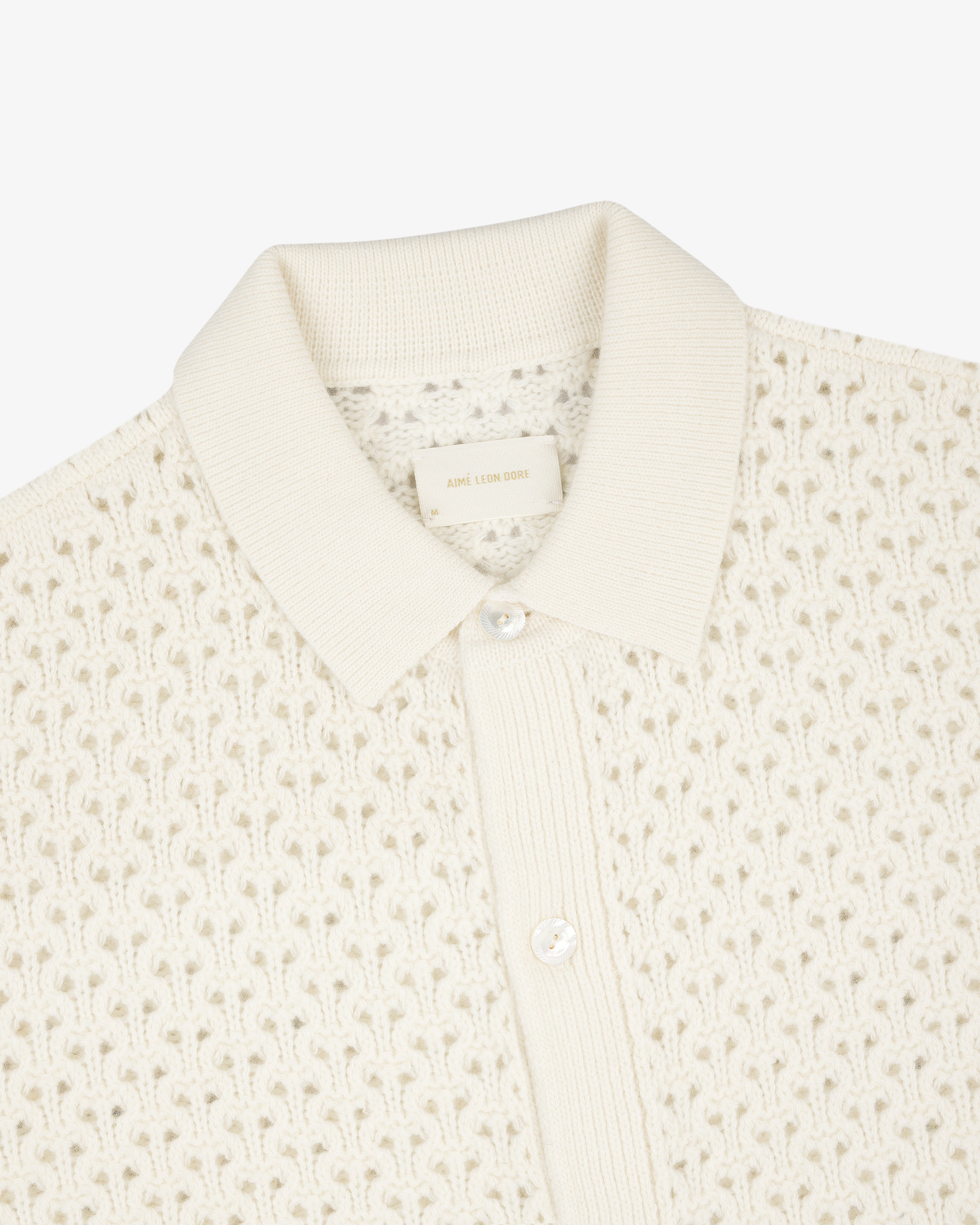 Cream knit polo cardigan with textured pattern, ribbed collar, and two-button placket.