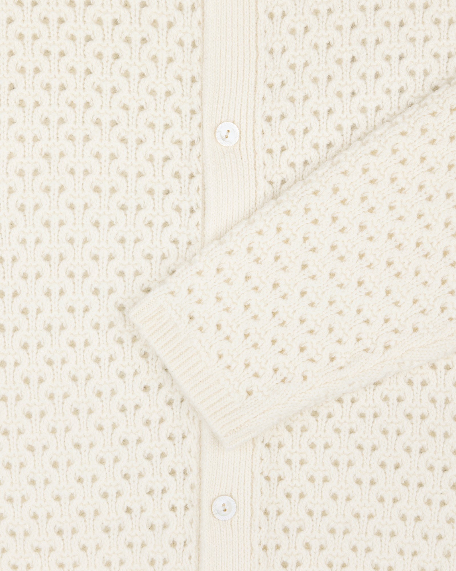 Close-up of the Knit Polo Cardigan with white buttons and textured, patterned stitching.