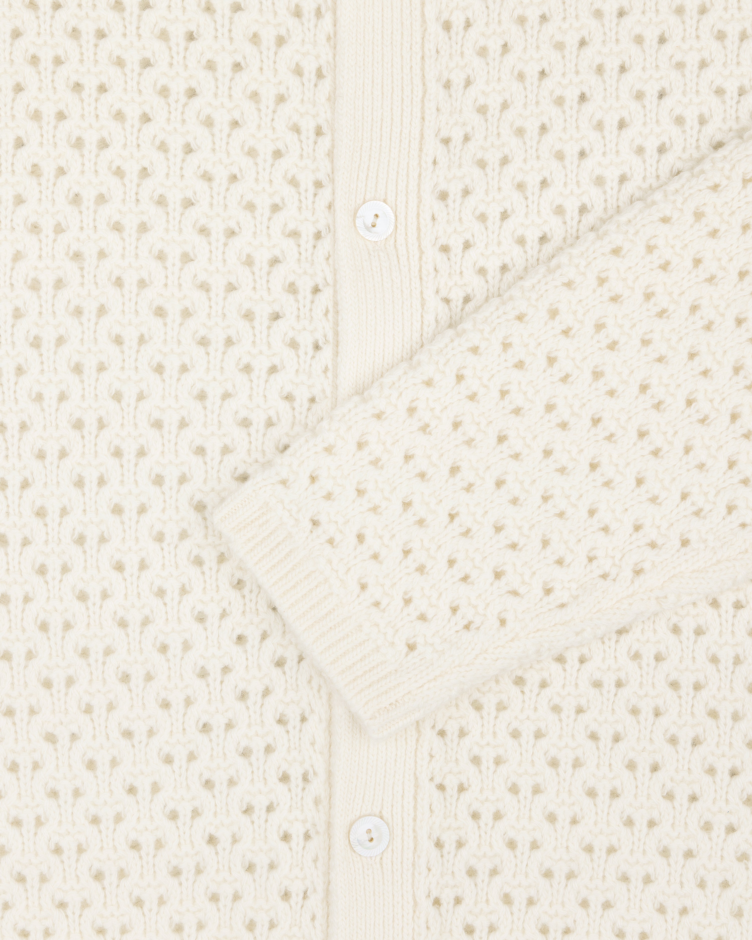 Close-up of the Knit Polo Cardigan with white buttons and textured, patterned stitching.