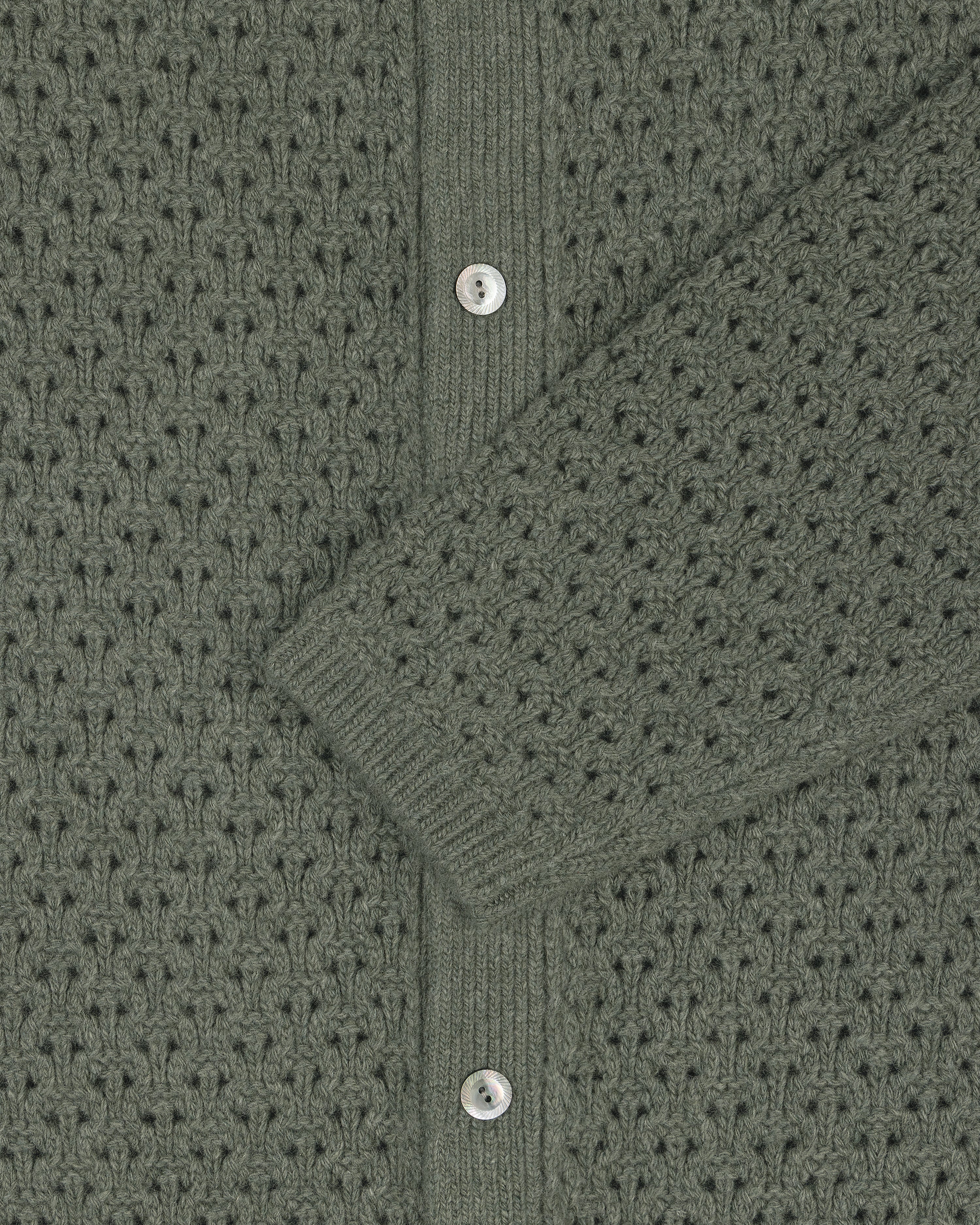 Close-up of a green Knit Polo Cardigan with silver buttons and a sleeve draped diagonally across the center.