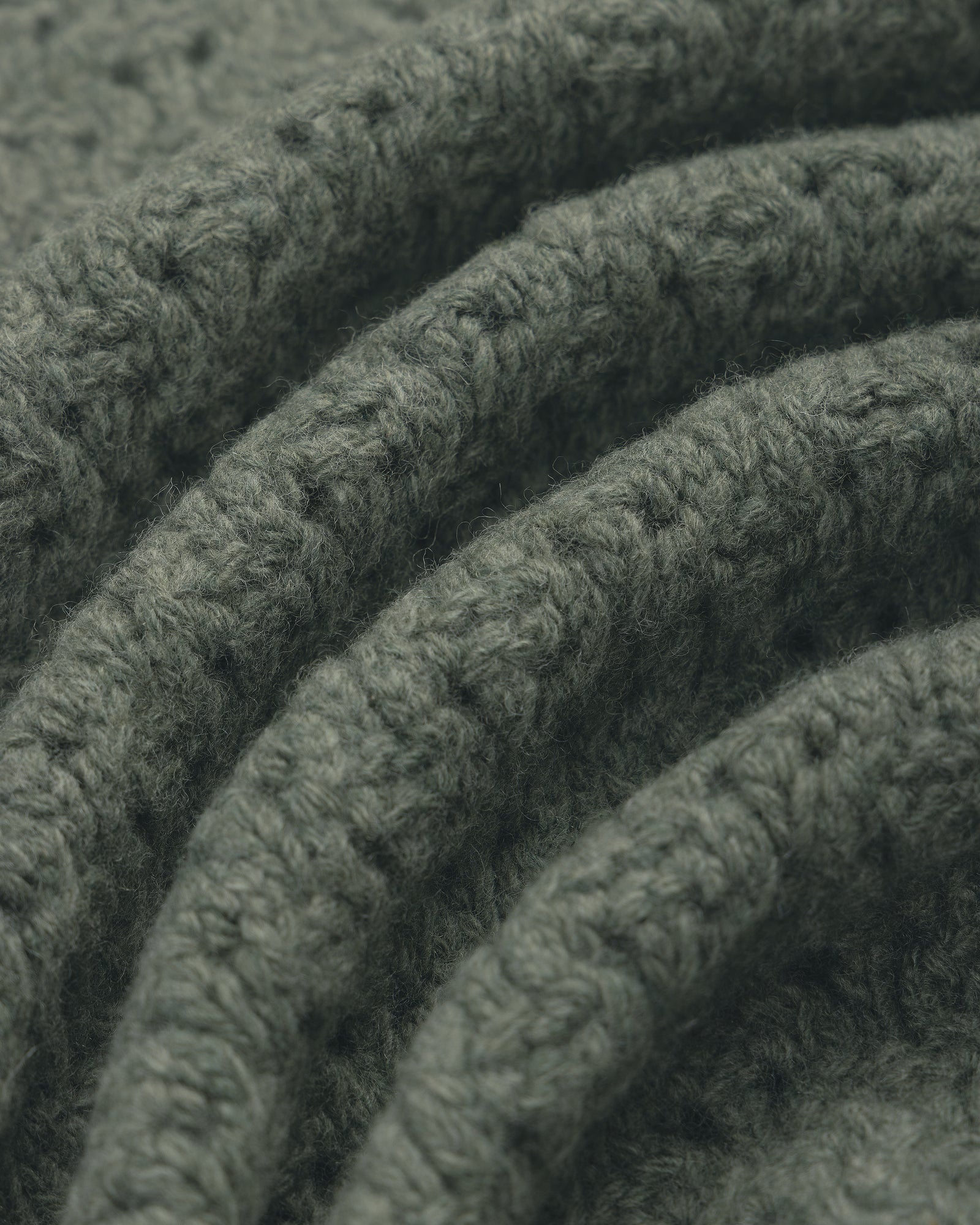 Close-up of folded green Knit Polo Cardigan, highlighting its textured stitches and cozy, soft feel.
