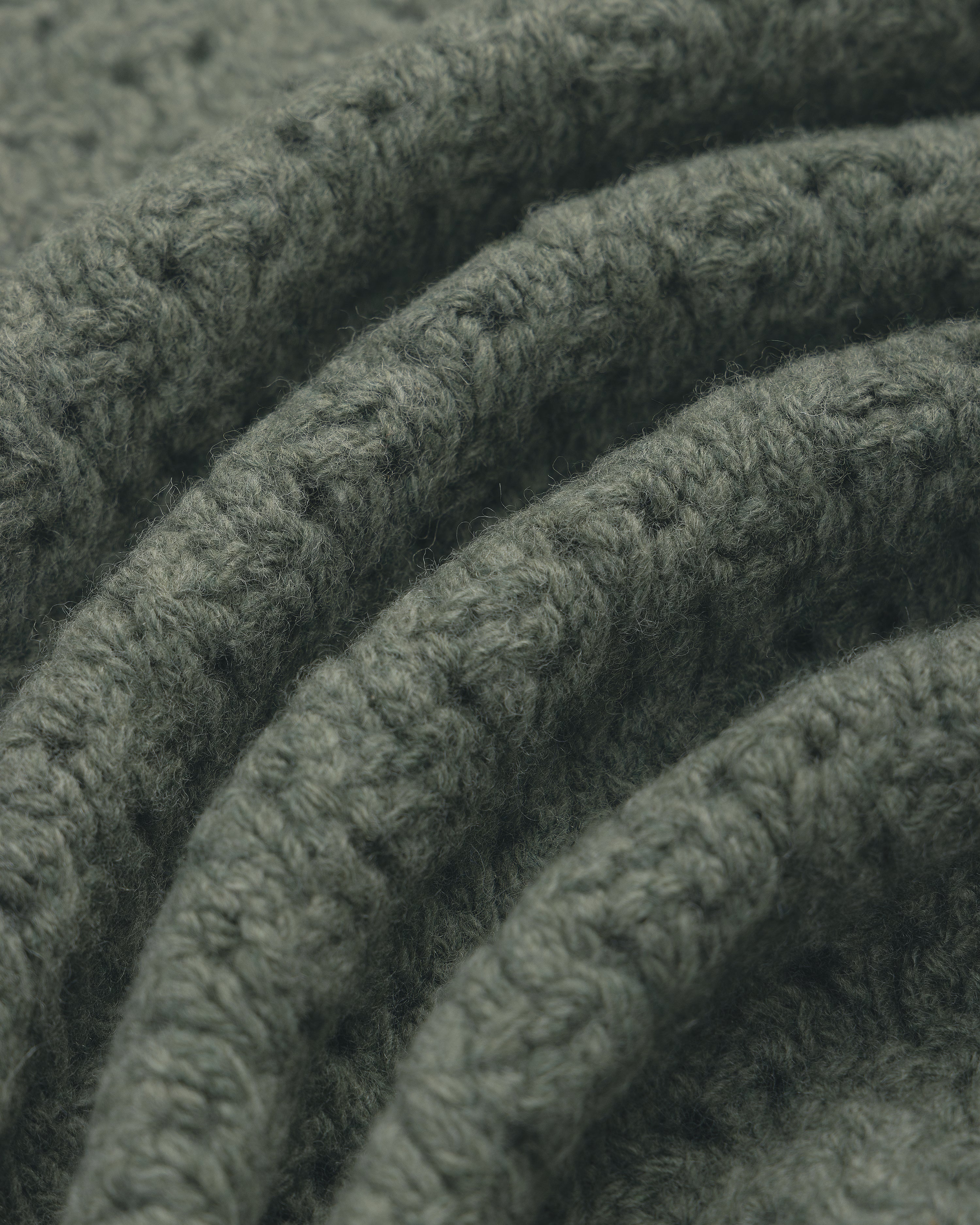 Close-up of folded green Knit Polo Cardigan, highlighting its textured stitches and cozy, soft feel.