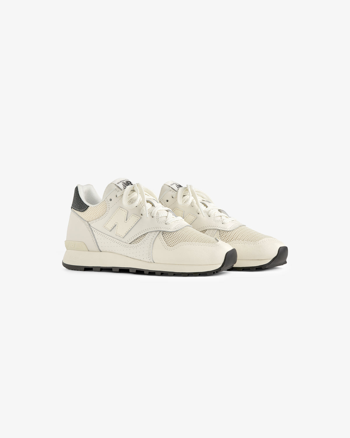 The ALD / New Balance 475 sneakers in off-white with beige accents and black soles, shown at a slight angle on white.