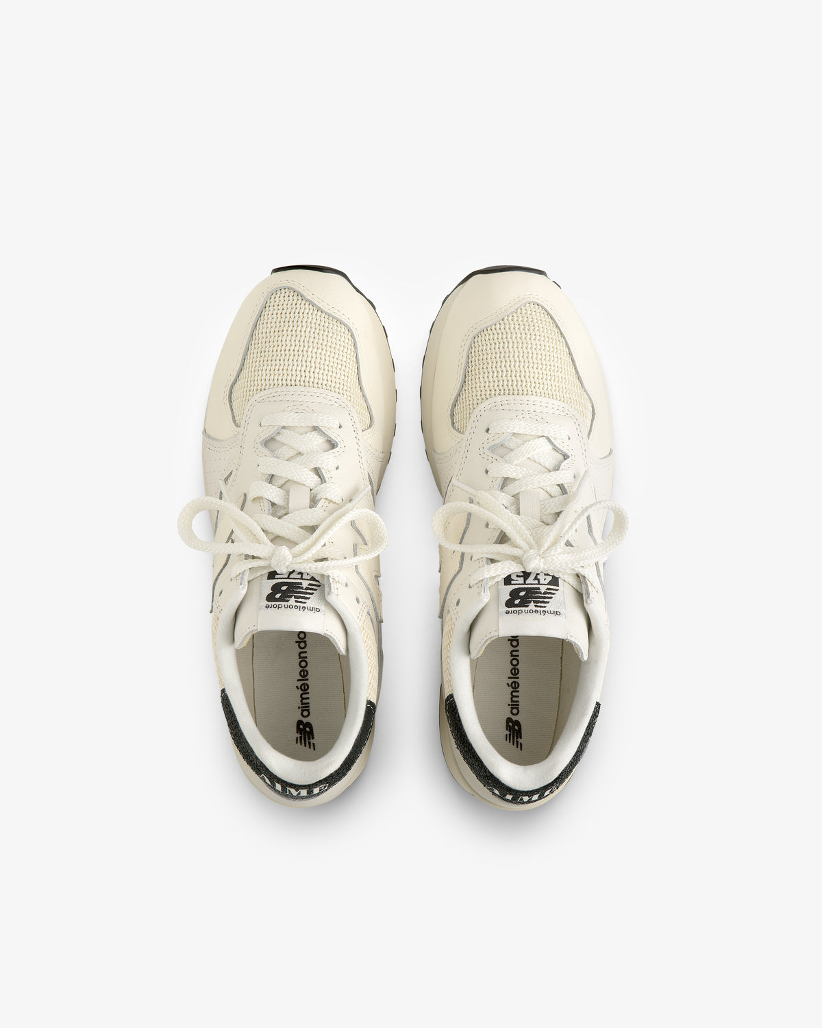 Top view of ALD / New Balance 475 white sneakers with tied laces, side by side on a white background.