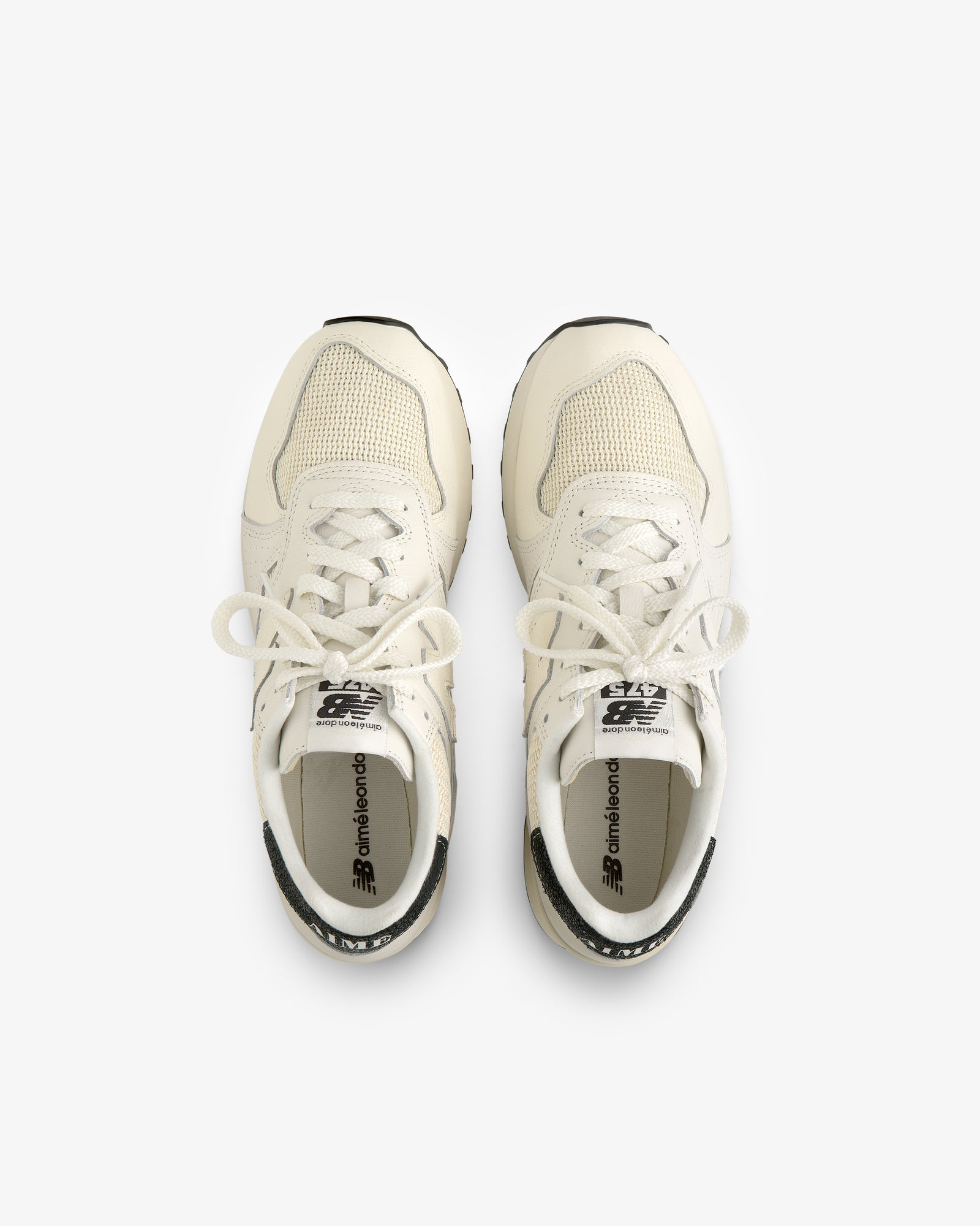 Top view of ALD / New Balance 475 white sneakers with tied laces, side by side on a white background.