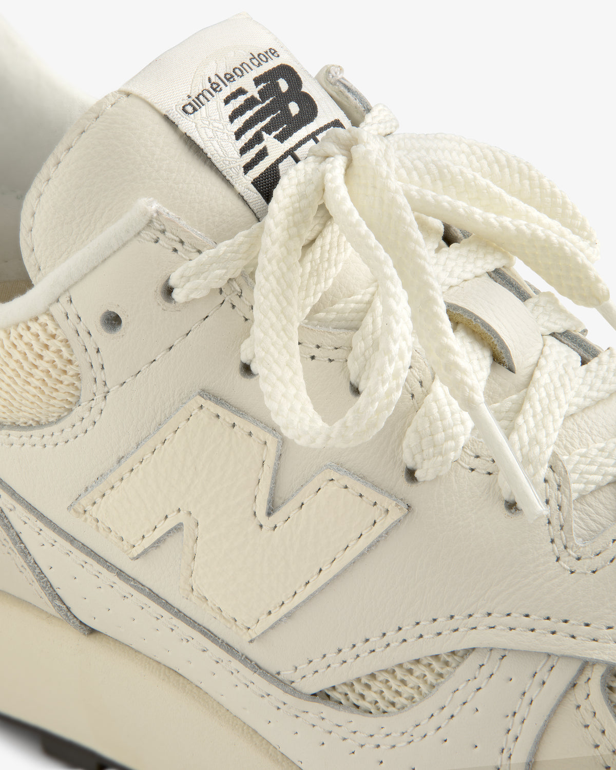Close-up of a cream-colored ALD / New Balance 475 sneaker with branded tongue and textured laces.