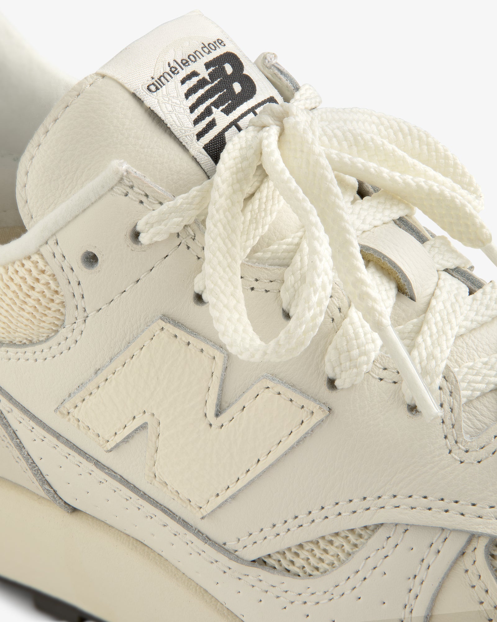 Close-up of a cream-colored ALD / New Balance 475 sneaker with branded tongue and textured laces.