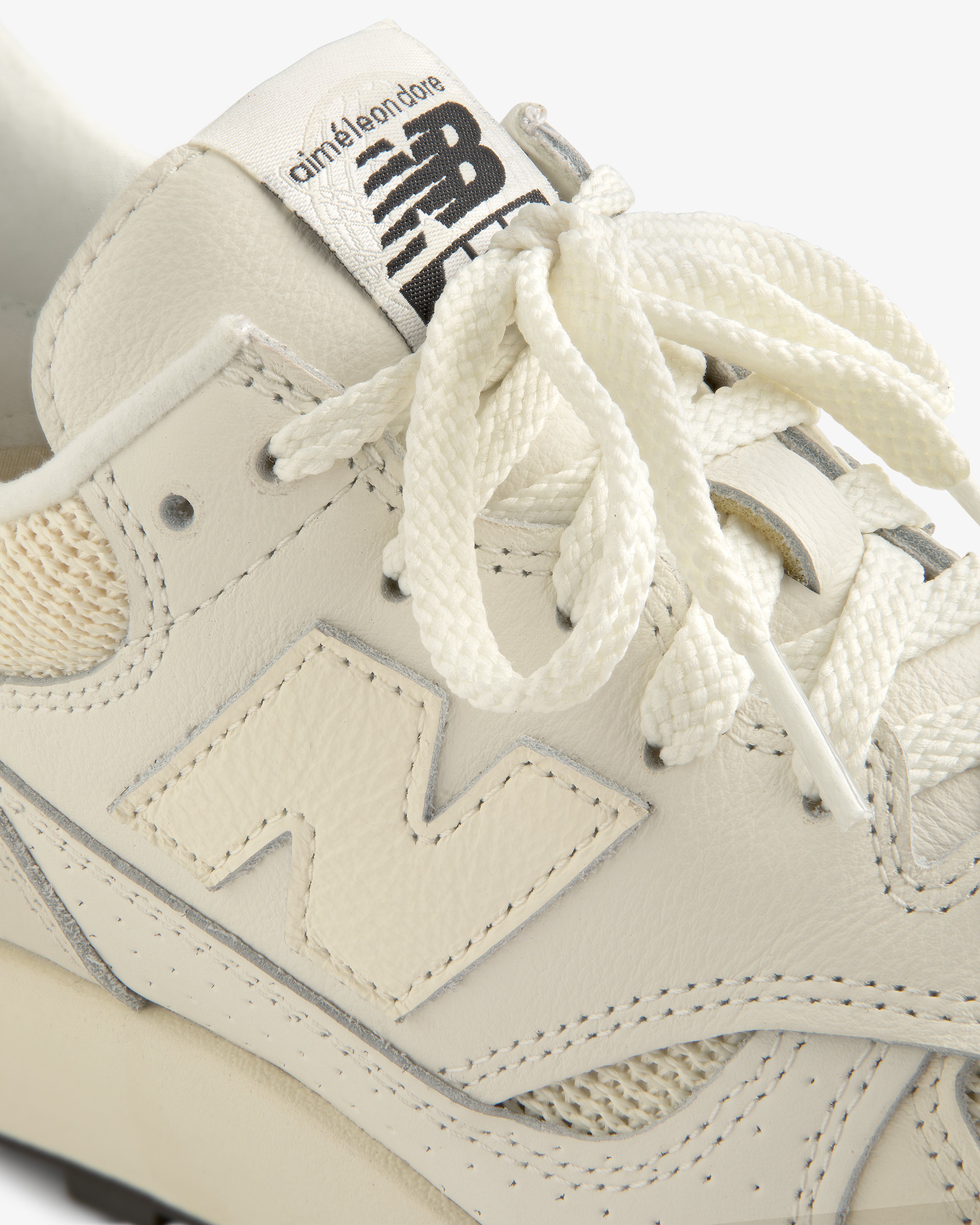 Close-up of a cream-colored ALD / New Balance 475 sneaker with branded tongue and textured laces.