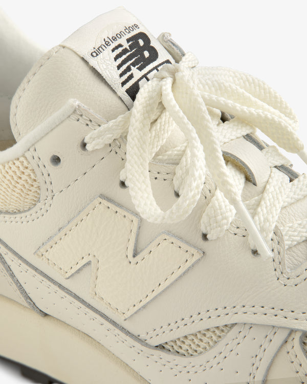 Close-up of a cream-colored ALD / New Balance 475 sneaker with branded tongue and textured laces.