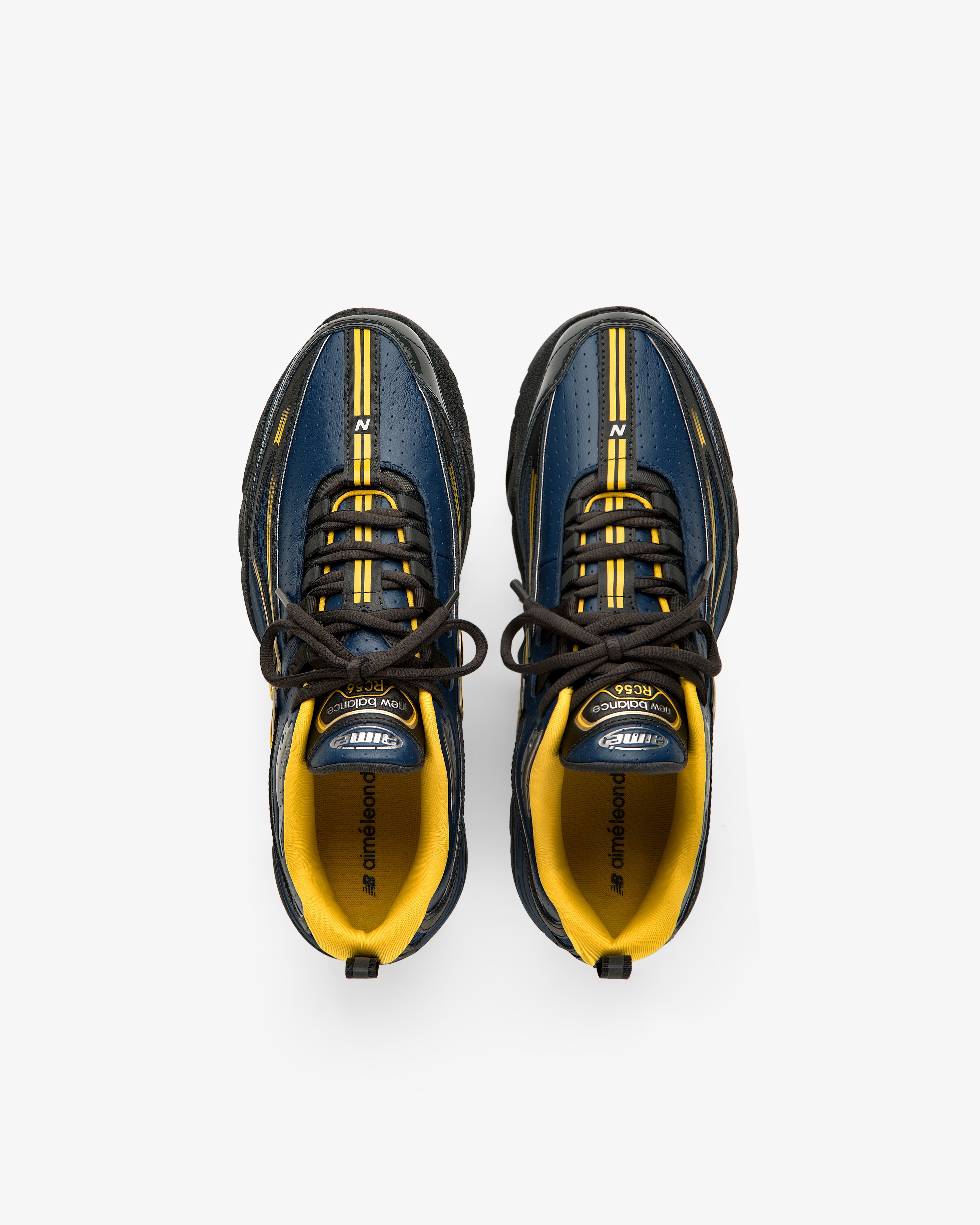 A pair of ALD / New Balance RC56 sneakers in blue, yellow, and black seen from above on a white background.