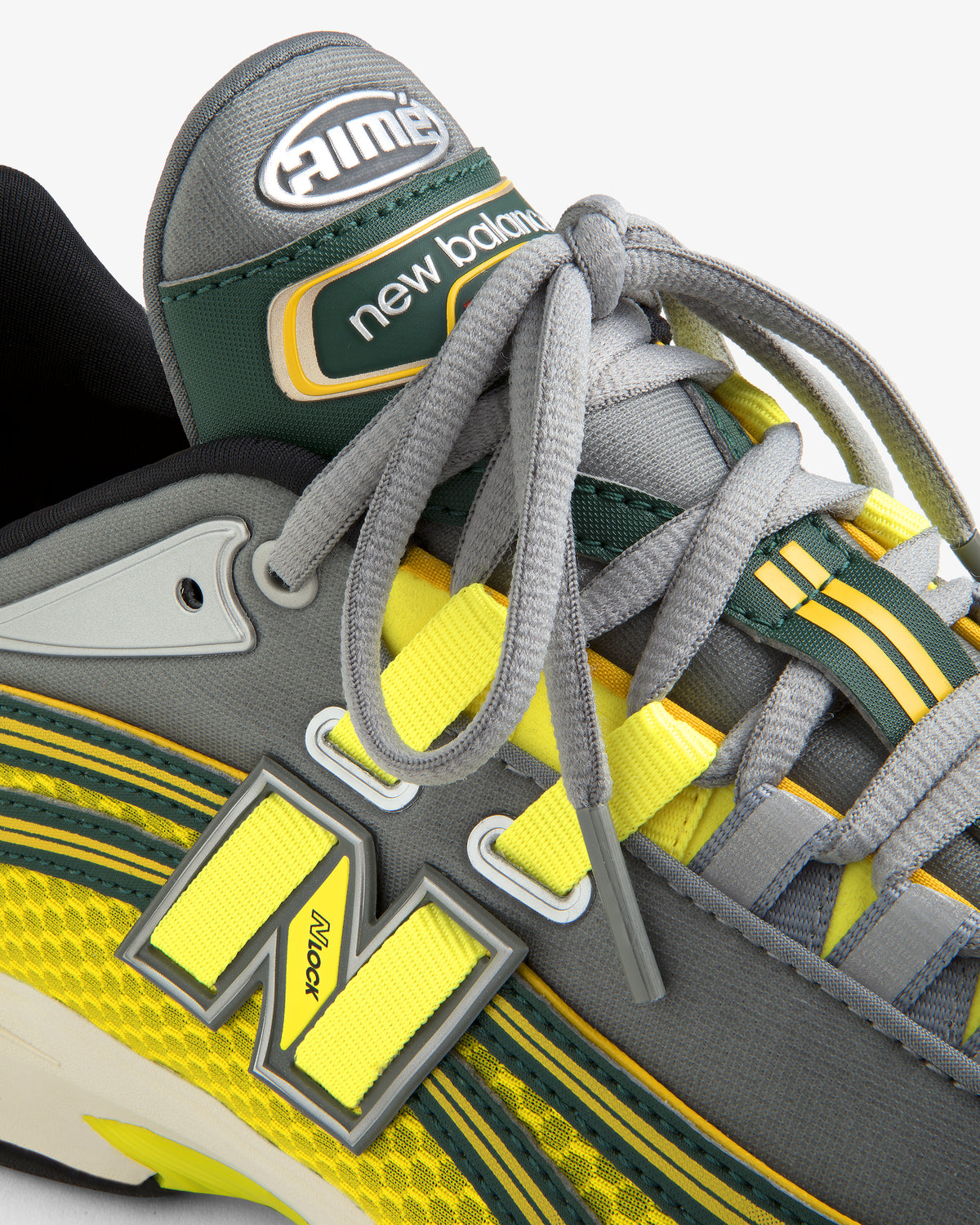 Close-up of the ALD / New Balance RC56 sneaker in gray, yellow, and green, highlighting laces, logo, and stitching.