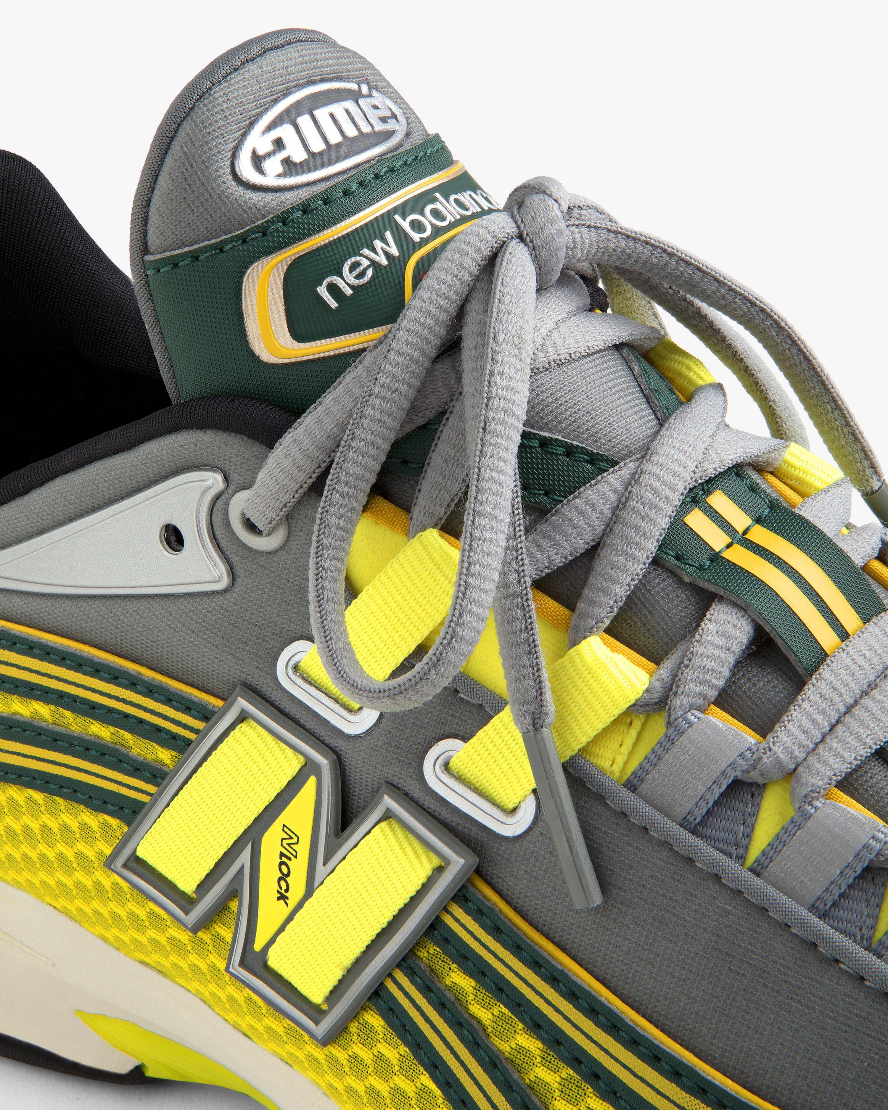 Close-up of the ALD / New Balance RC56 sneaker in gray, yellow, and green, highlighting laces, logo, and stitching.