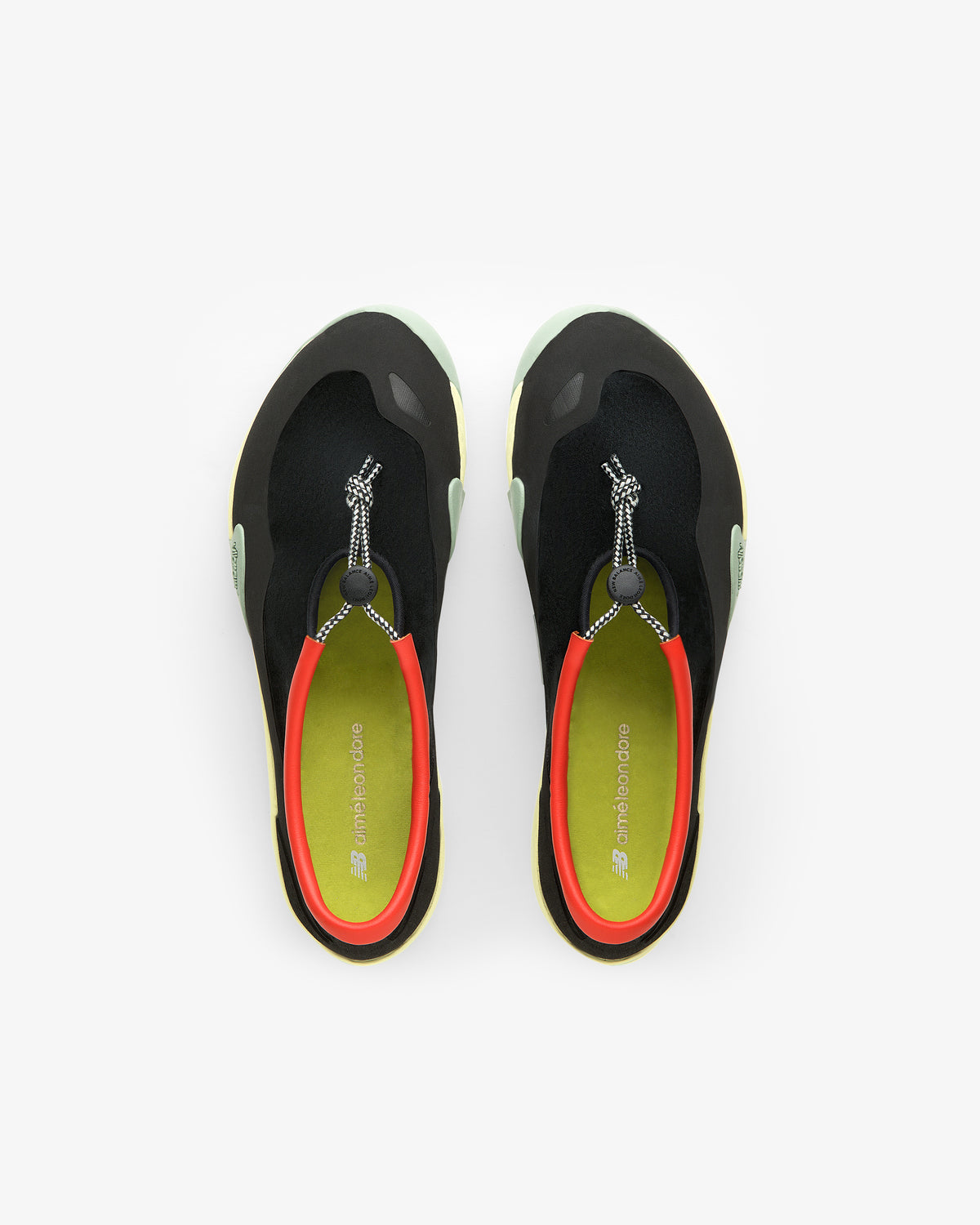 Top view of ALD / New Balance MT10T Sport Shoe in black with red trim, green soles, and toggle laces on white.