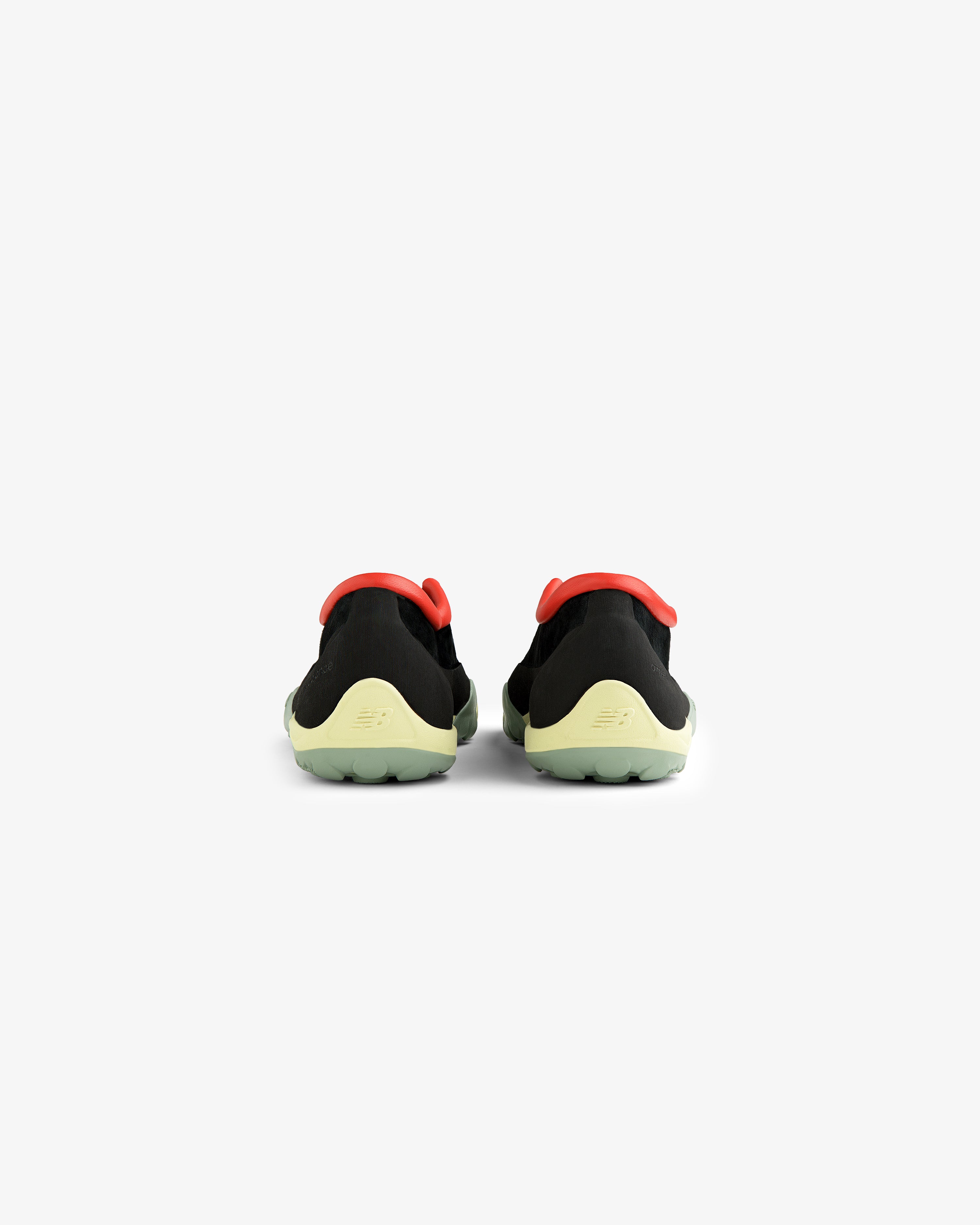 The ALD / New Balance MT10T Sport Shoe features black uppers, yellow-green soles, and red accents, seen from the back.