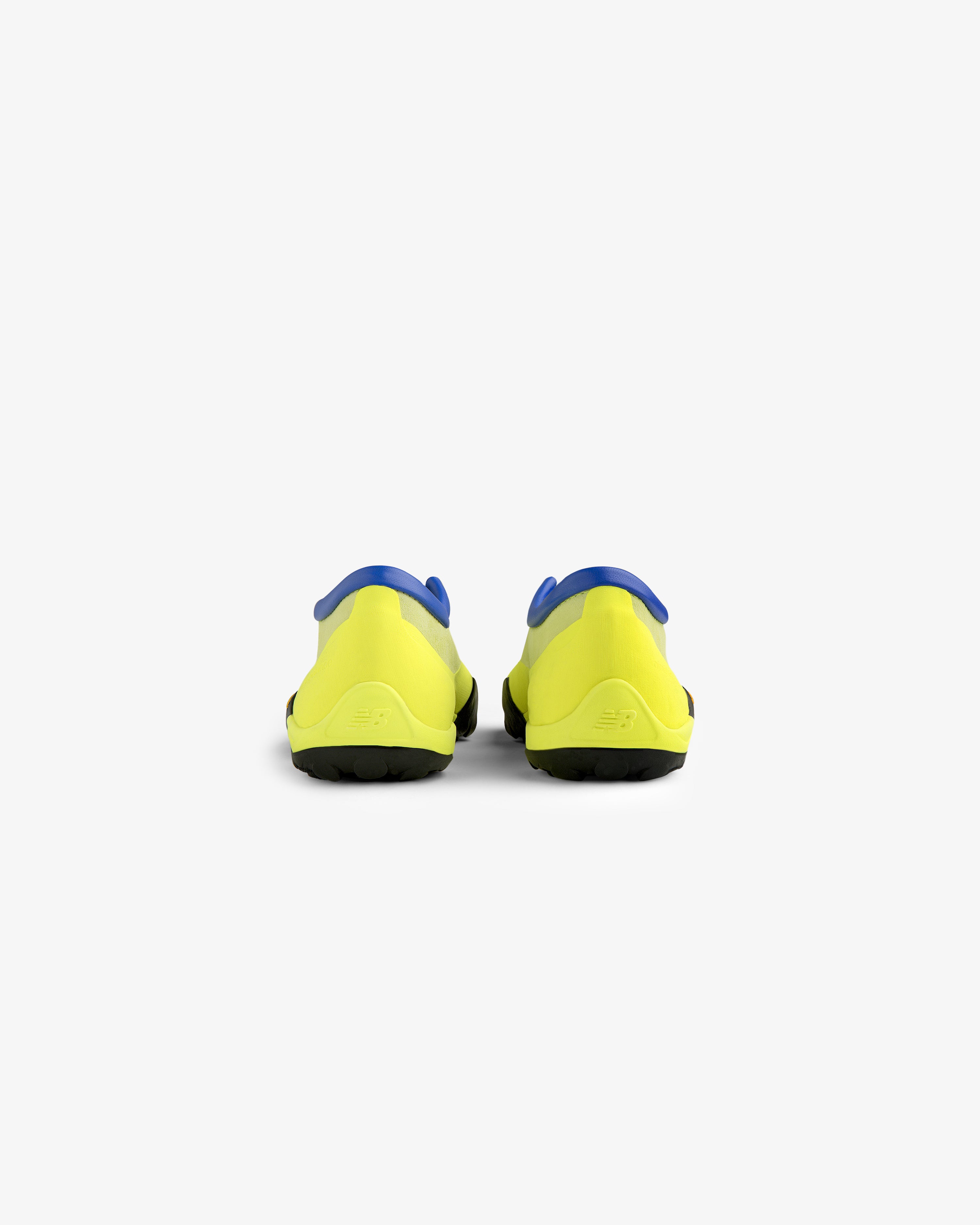 Rear view of ALD / New Balance MT10T Sport Shoes—yellow with blue accents and black soles on white background.