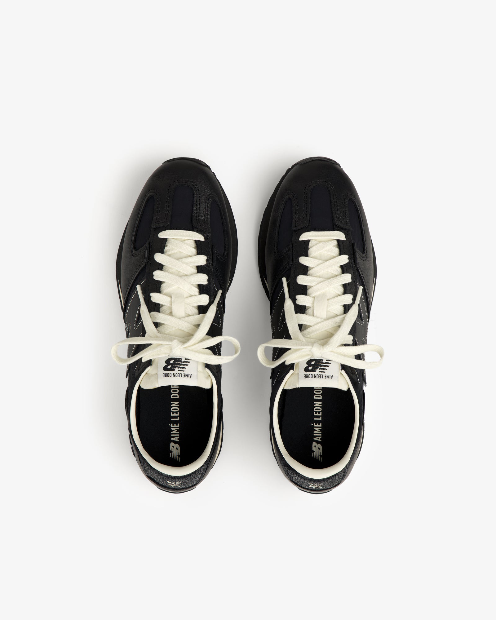 A pair of ALD / New Balance 471 black sneakers with white laces, viewed from above on a white backdrop.