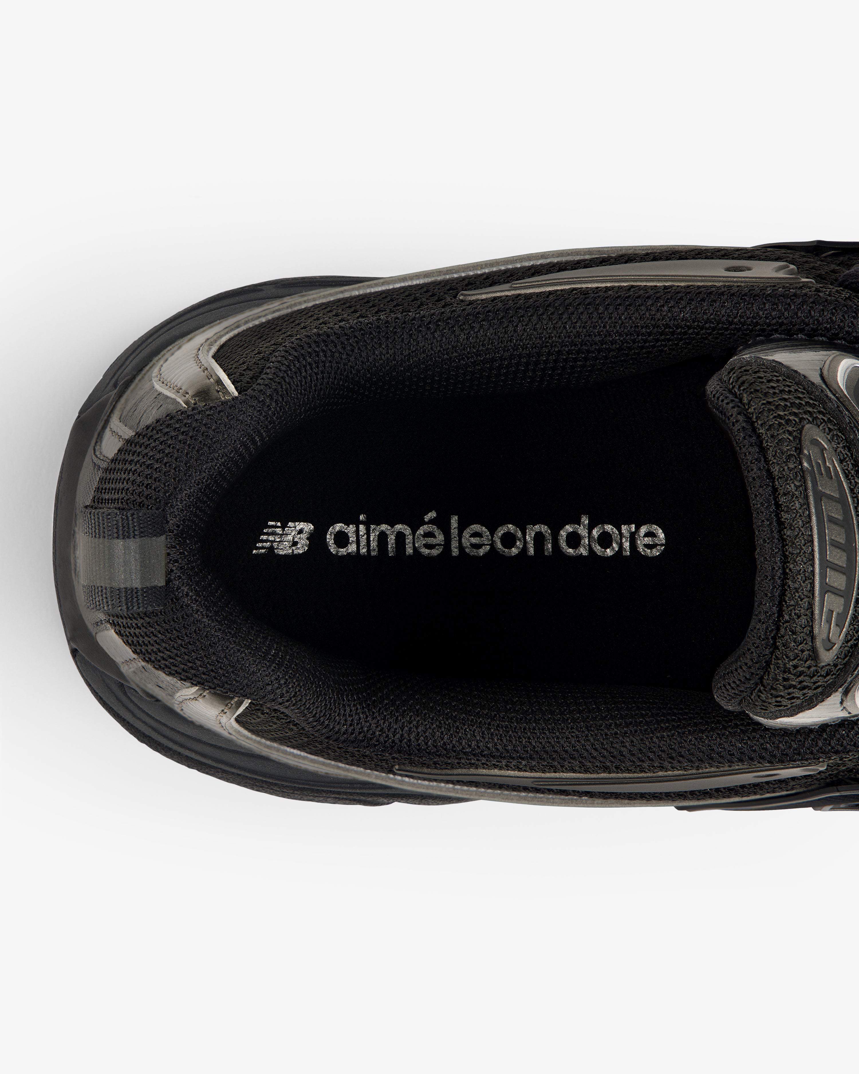Top view of a black ALD / New Balance RC56 sneaker with "aimé leon dore" printed in white on the insole.